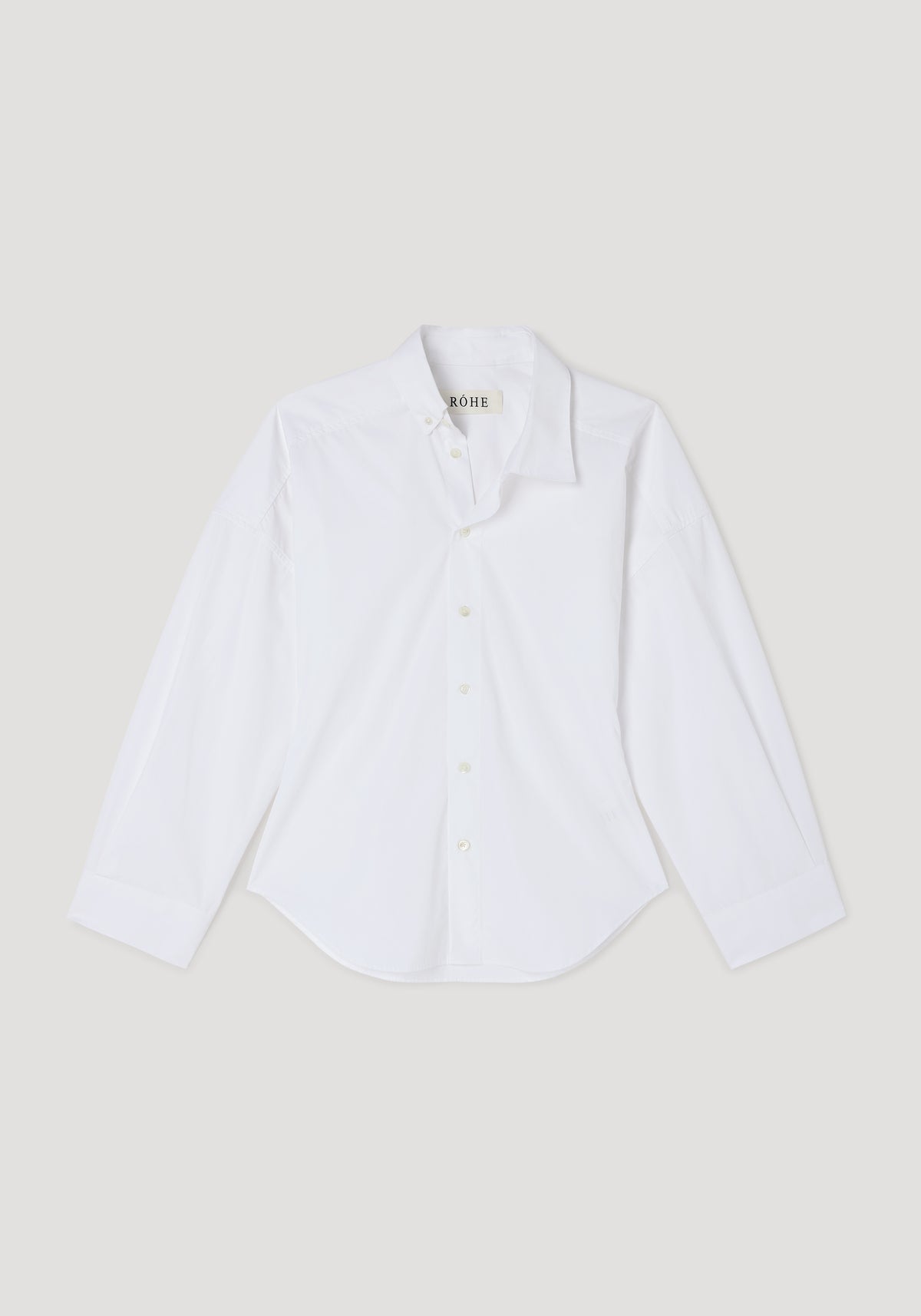 White long-sleeve button-up shirt with an asymmetric collar design, displayed flat on a neutral background, showcasing the Poplin uneven collar shirt | optic white style.