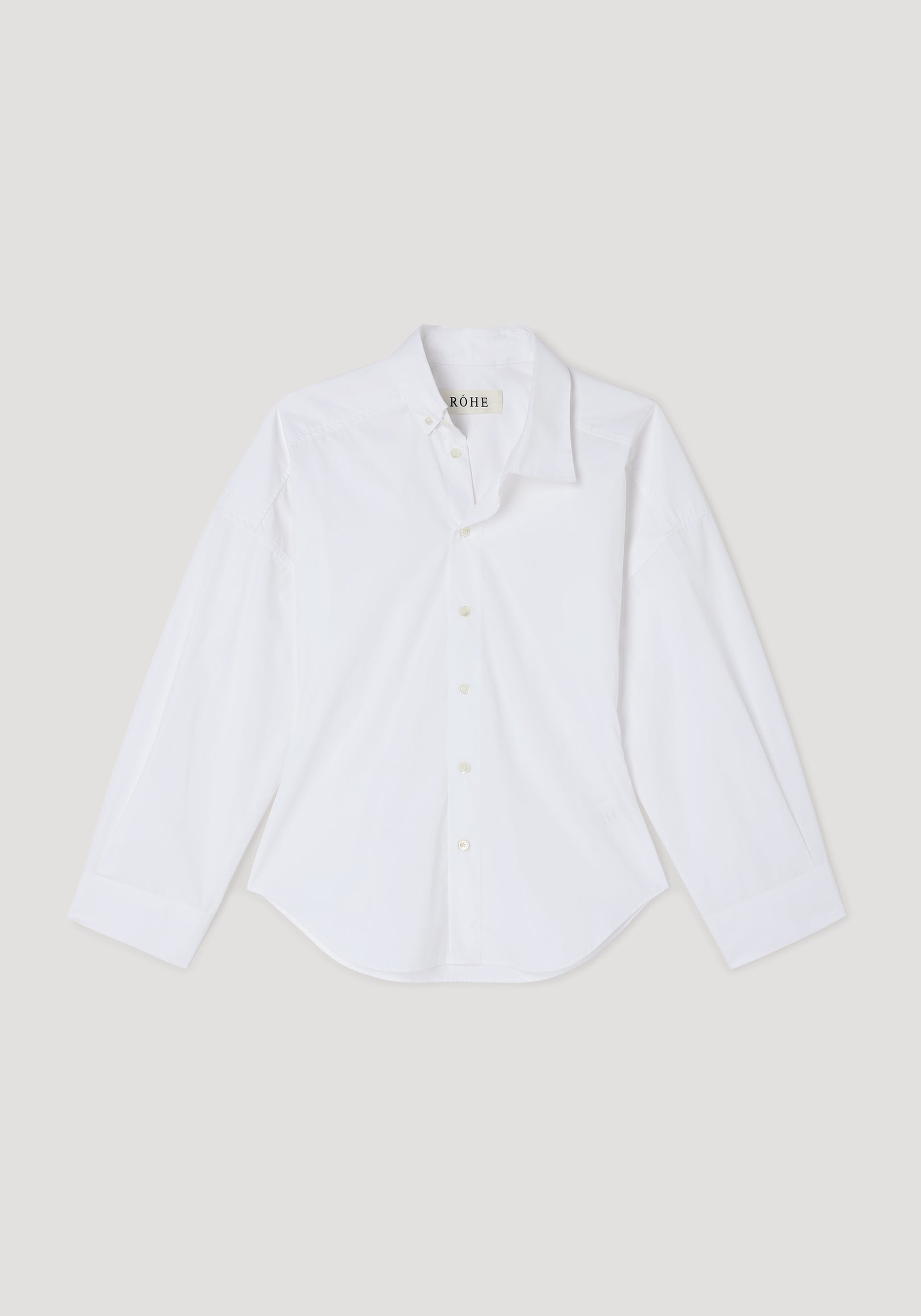 White long-sleeve button-up shirt with an asymmetric collar design, displayed flat on a neutral background, showcasing the Poplin uneven collar shirt | optic white style.