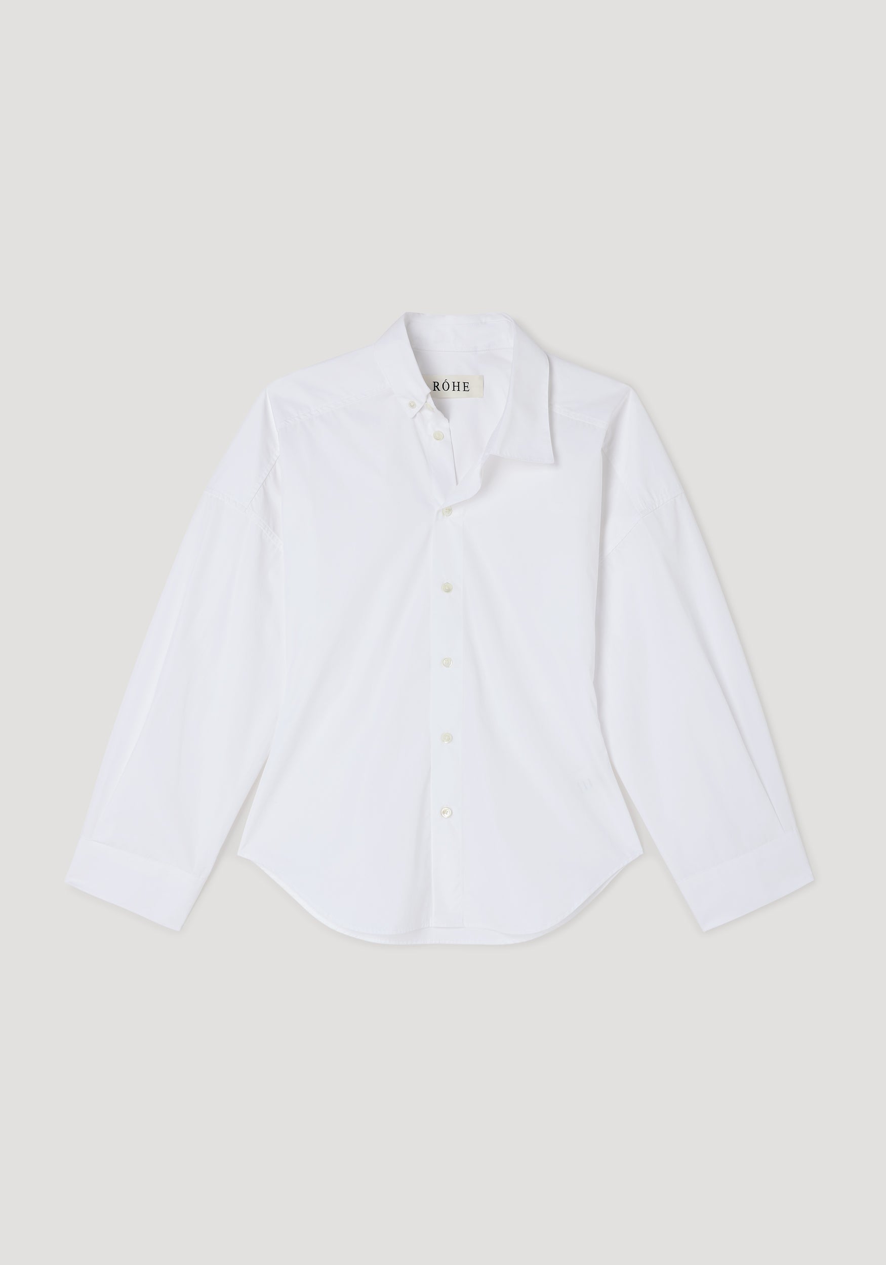 White long-sleeve button-up shirt with an asymmetric collar design, displayed flat on a neutral background, showcasing the Poplin uneven collar shirt | optic white style.