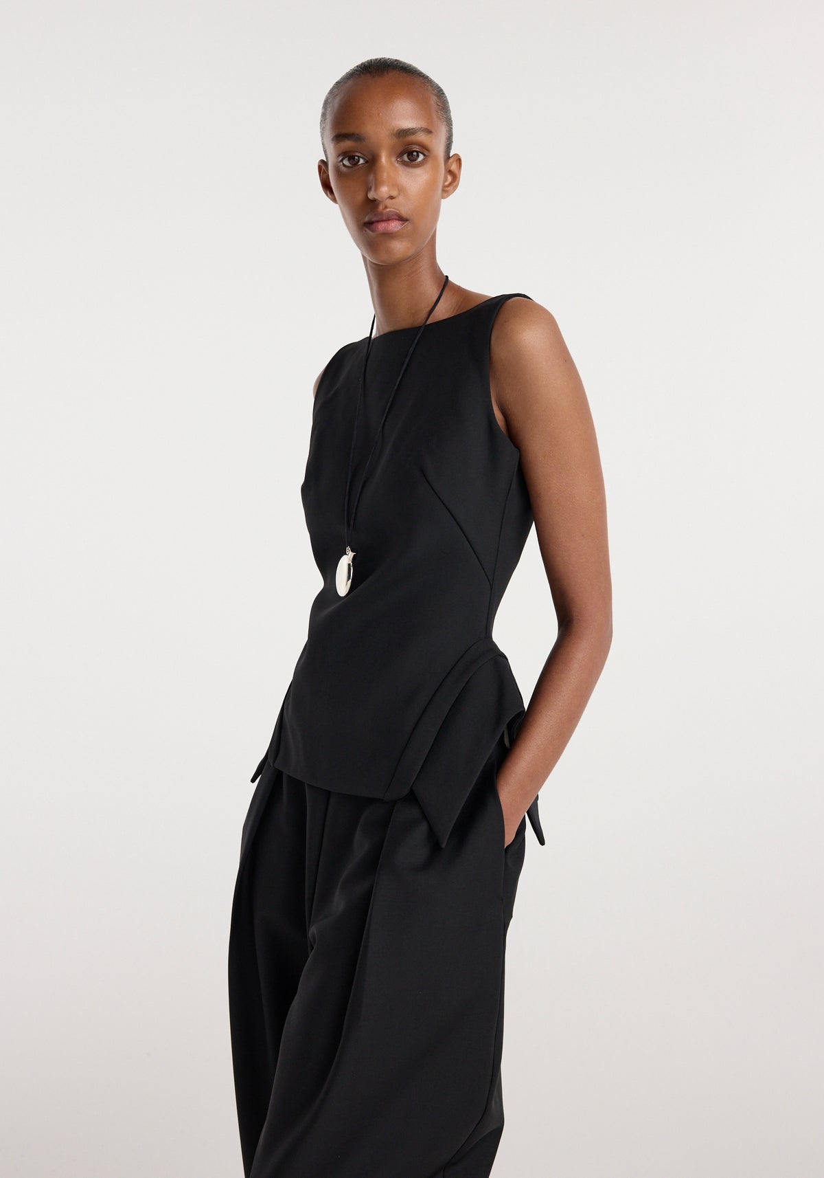 Model wearing a black sleeveless top with a unique deconstructed collar and tailored fit paired with loose black pants, styled with a pendant necklace, showcasing the Deconstructed collar top | black.
