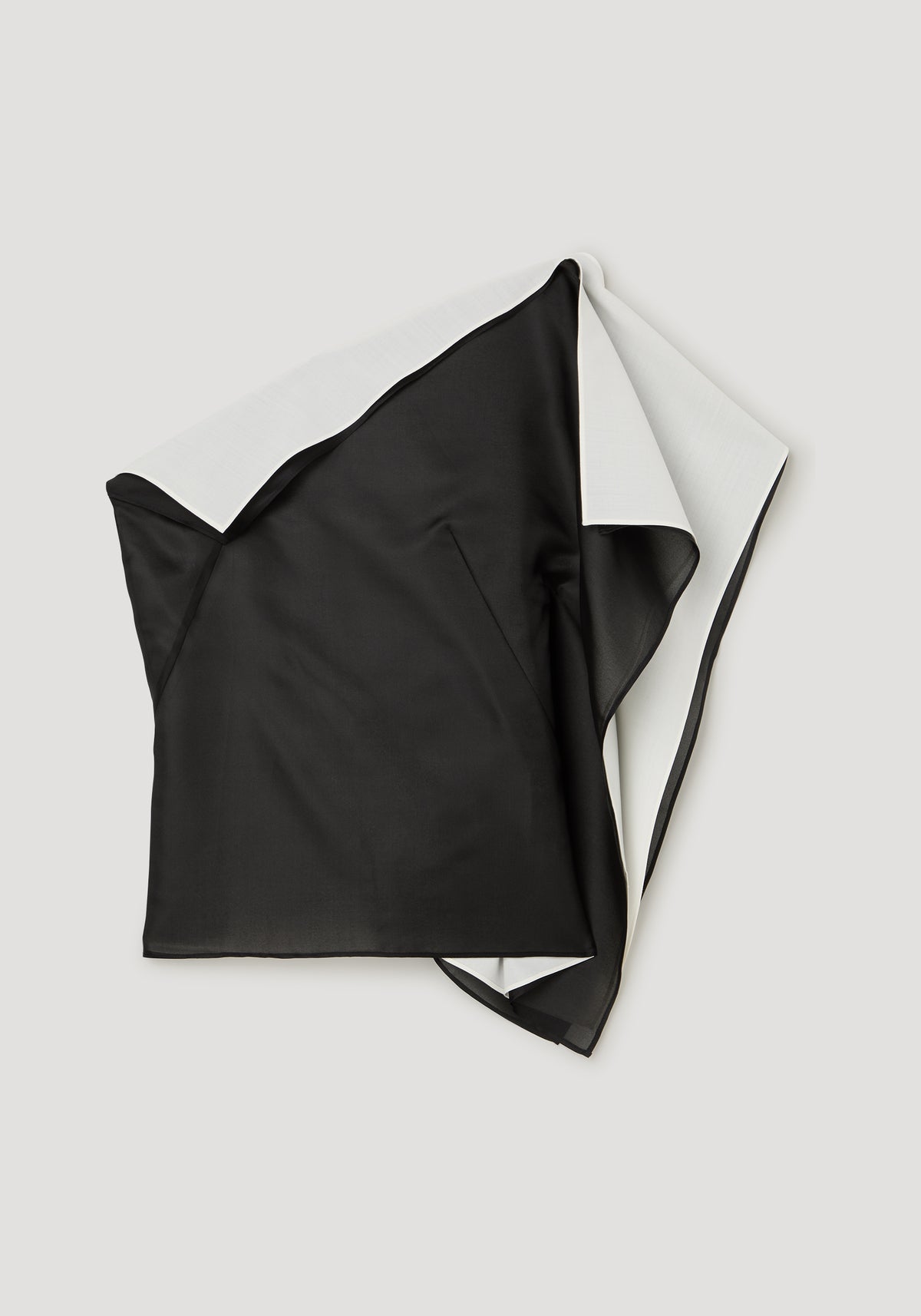 Sculptural double layered top | black shown flat with an asymmetrical silhouette and contrasting light inner layer visible at the side and hem
