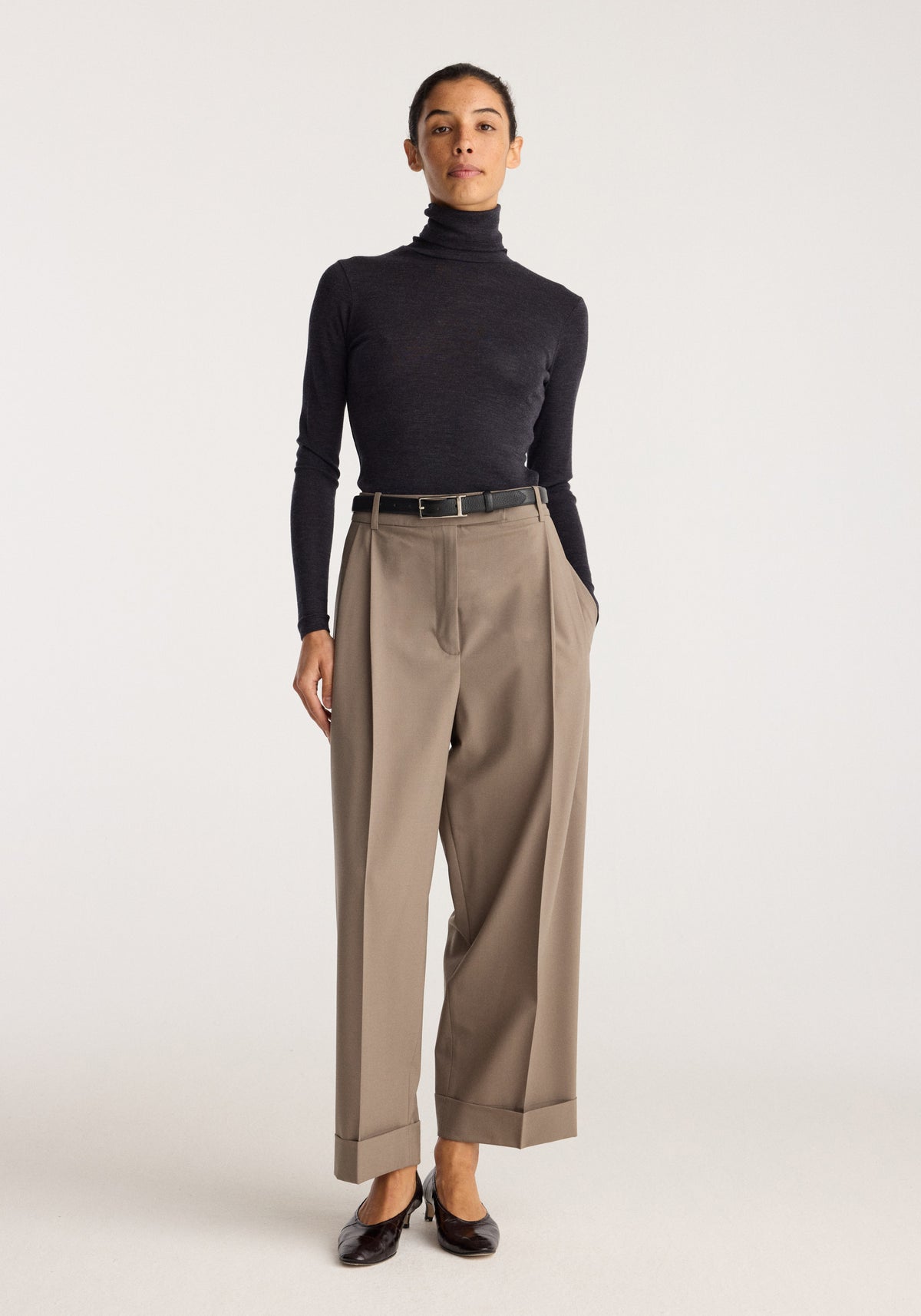 Fine merino turtleneck | anthracite melange worn by a model with tailored taupe trousers and black loafers against a neutral studio background