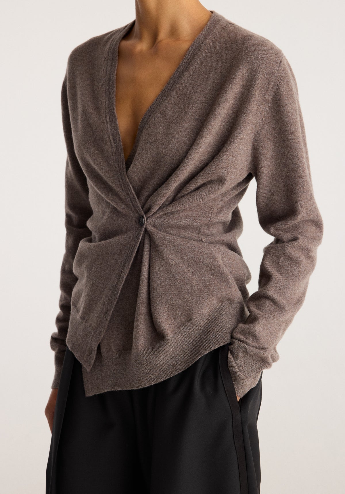 Twisted ballet cardigan | mud in muted brown with a wrap front twisted waist tie long sleeves and a model wearing black trousers