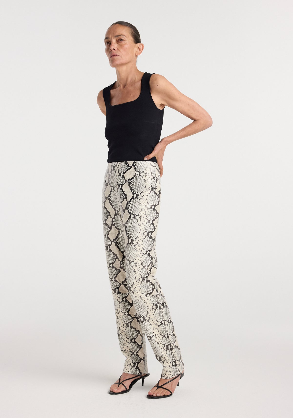 Snakeskin leather trousers | snakeskin worn by a model with a black sleeveless top and strappy heels in a studio setting