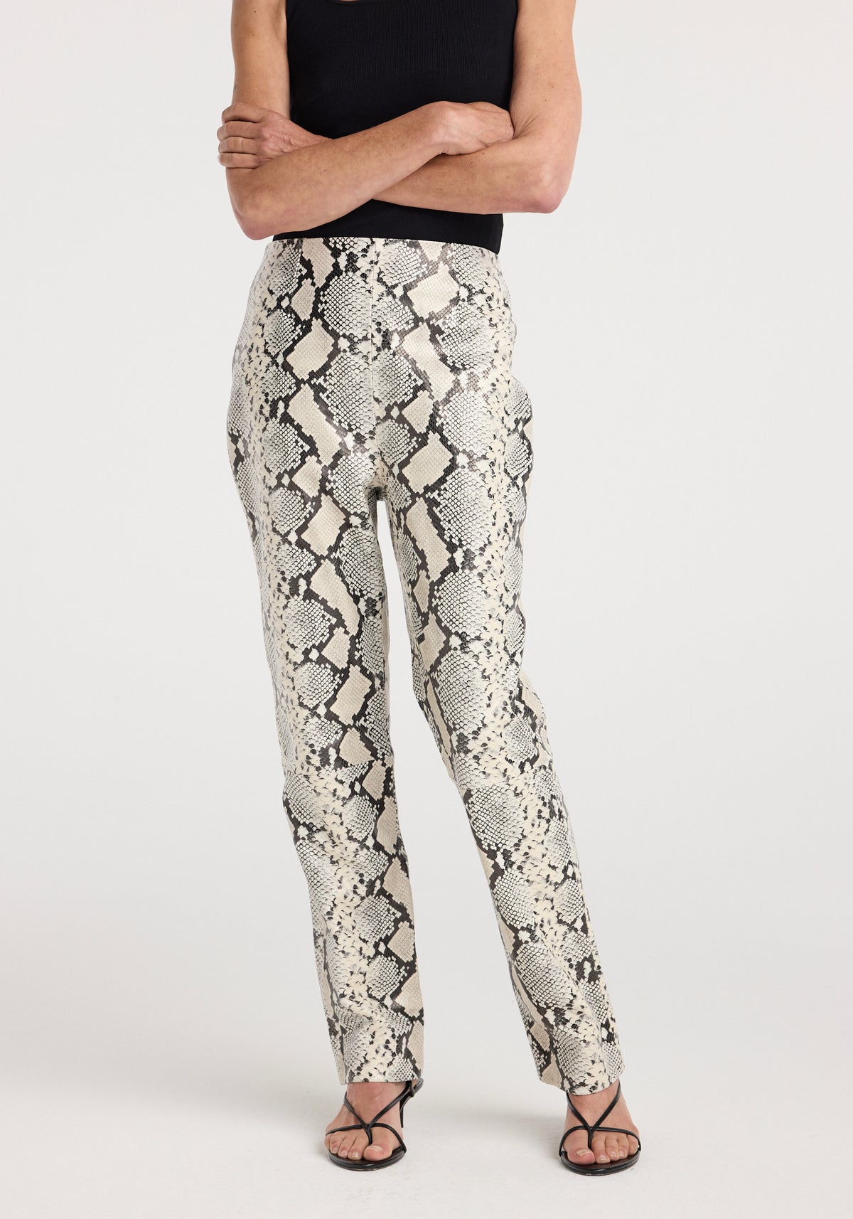 Snakeskin leather trousers | snakeskin worn by a model with a black top and strappy sandals, showcasing the fitted snakeskin pattern and slim leg design