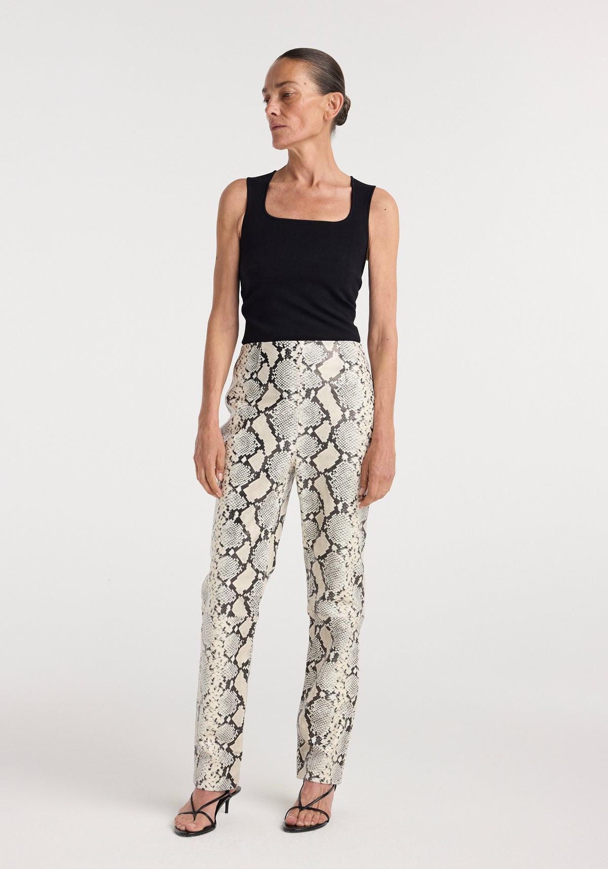 Model wearing snakeskin print leather trousers with a black sleeveless top and flat sandals, Snakeskin leather trousers | snakeskin