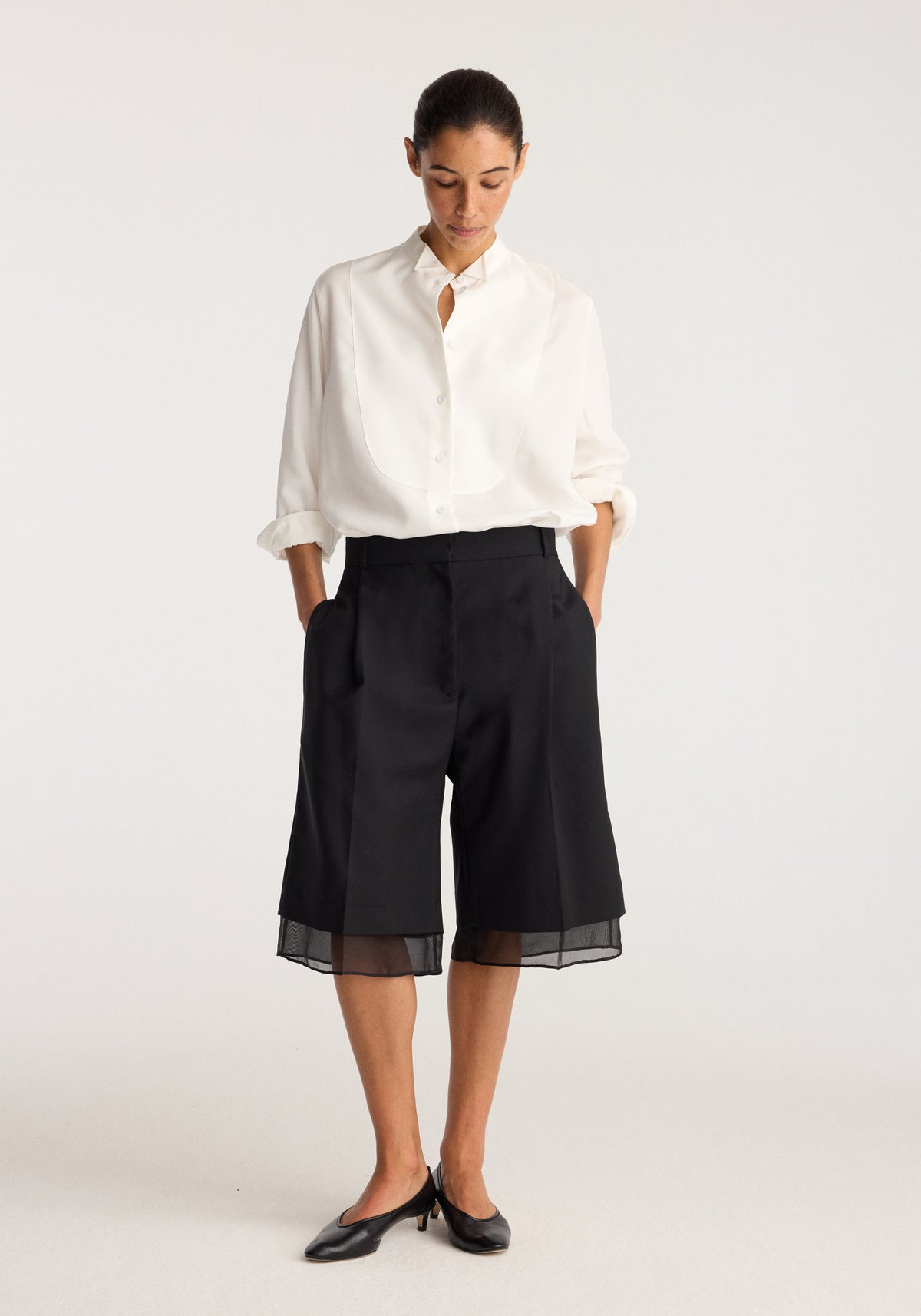 Model wearing Organza lined shorts | black with a sheer organza hem styled with a white button up shirt and black flats