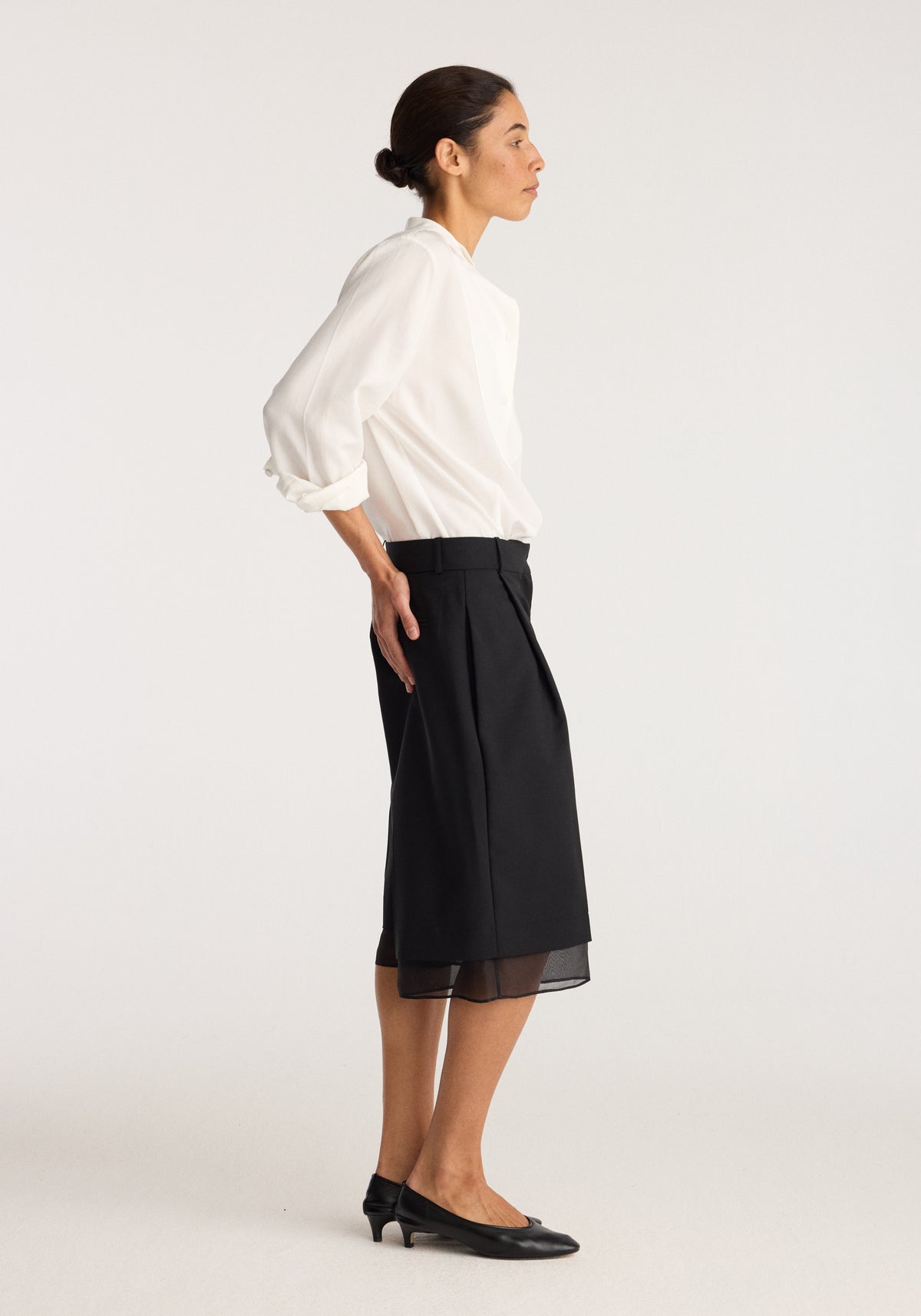 Organza lined shorts | black worn by a model with a white blouse and black flats showing the sheer organza hem detail