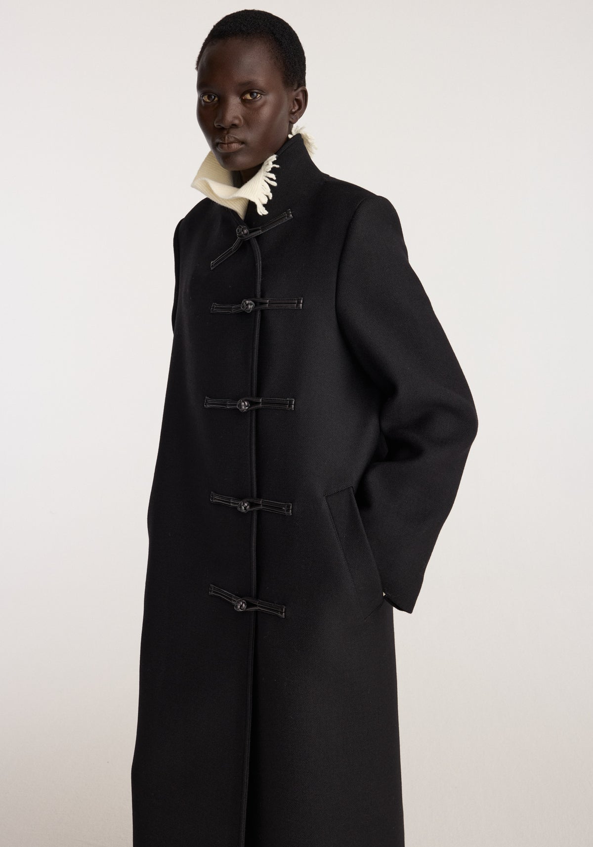 Pankou closure wool coat | black worn by a model featuring a long silhouette high collar and multiple front pankou closures
