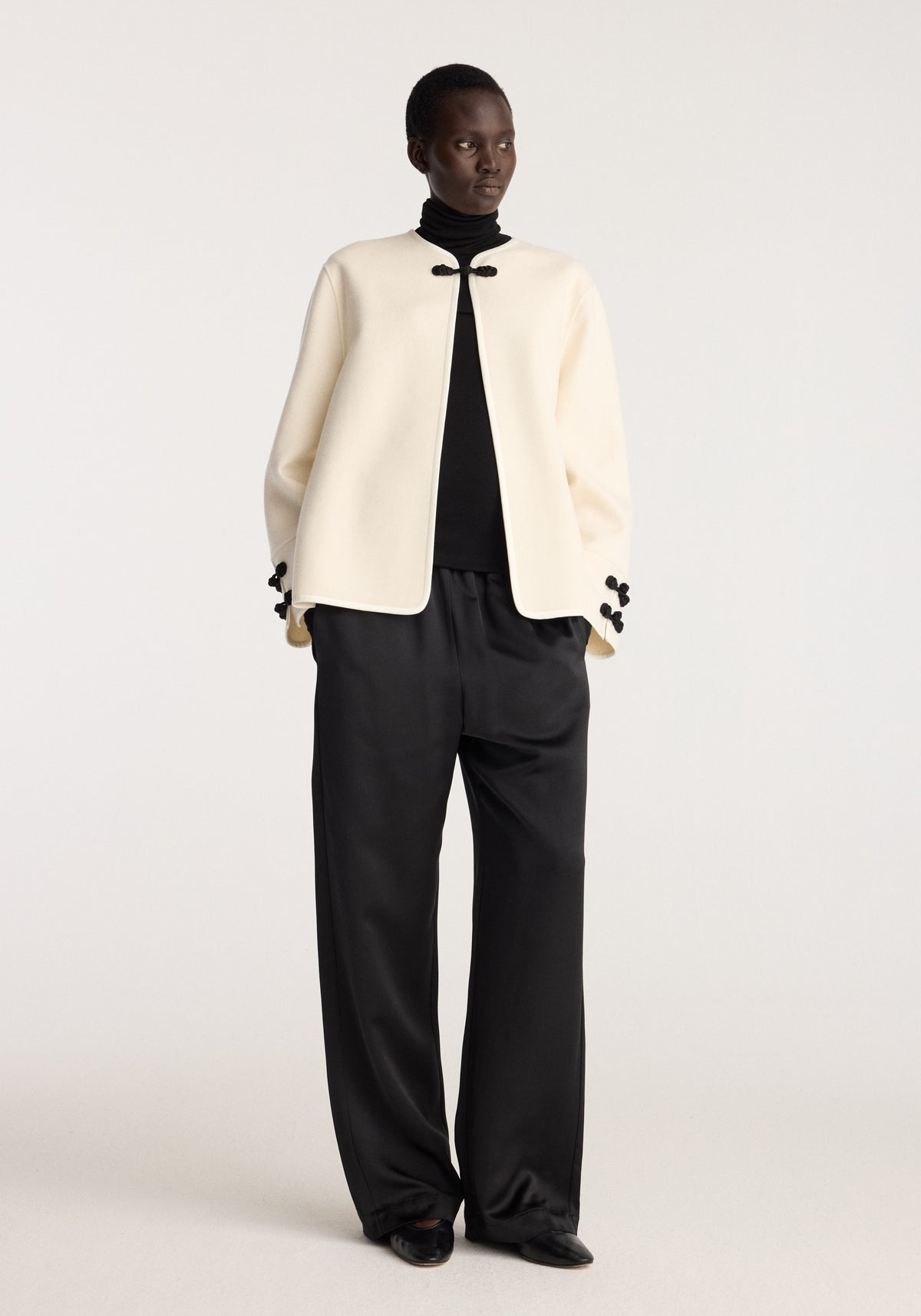 Double-faced pankou jacket | off white worn by a model with black trousers showing its cream color and distinctive pankou closures at the collar and cuffs