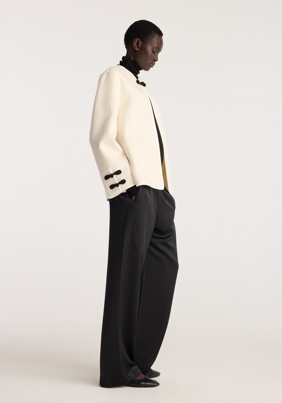 Double-faced pankou jacket | off white shown in side profile with black trim and button details styled with relaxed black trousers