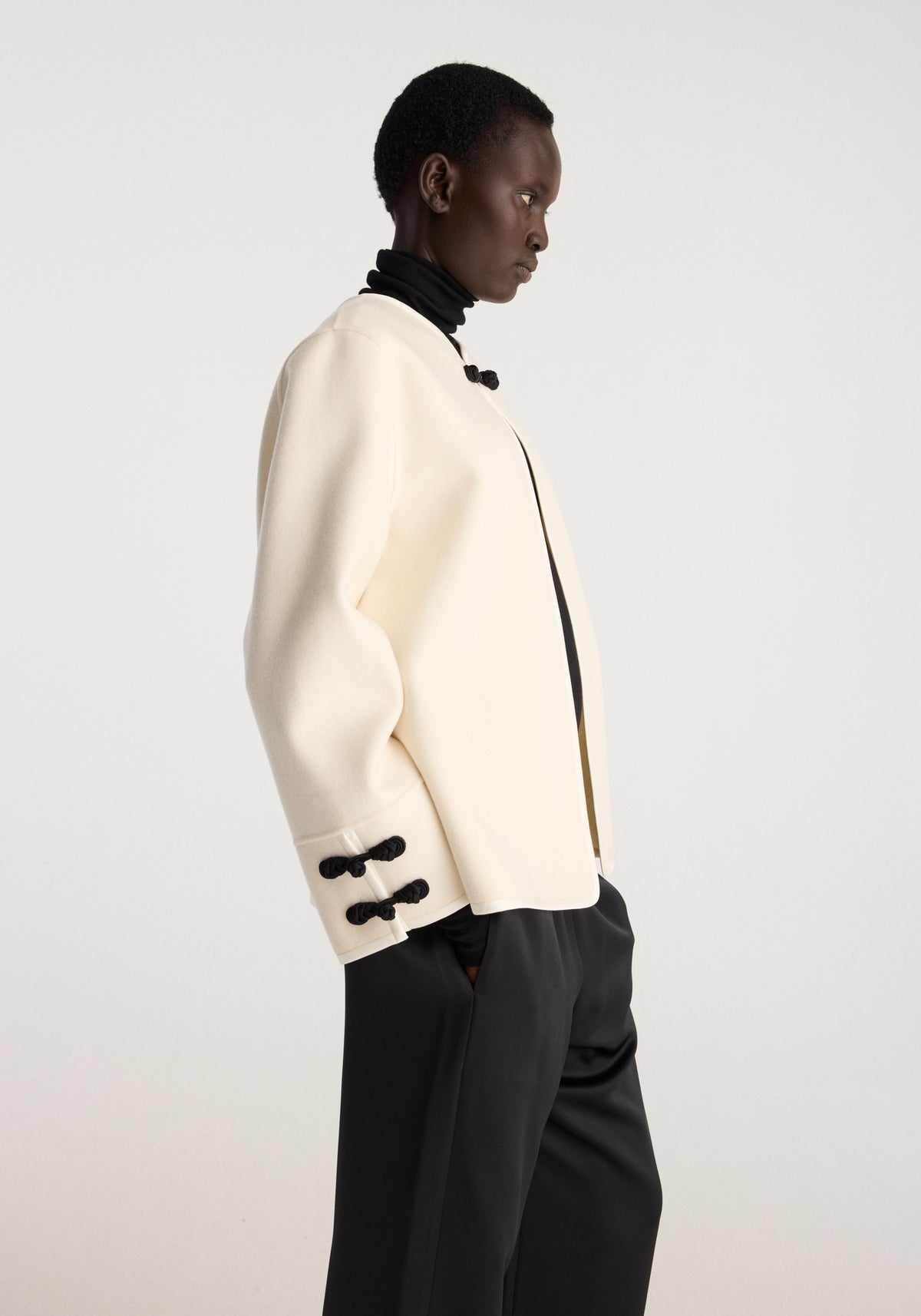 Double-faced pankou jacket | off white shown in side profile with black closures curved hem black scarf and black trousers