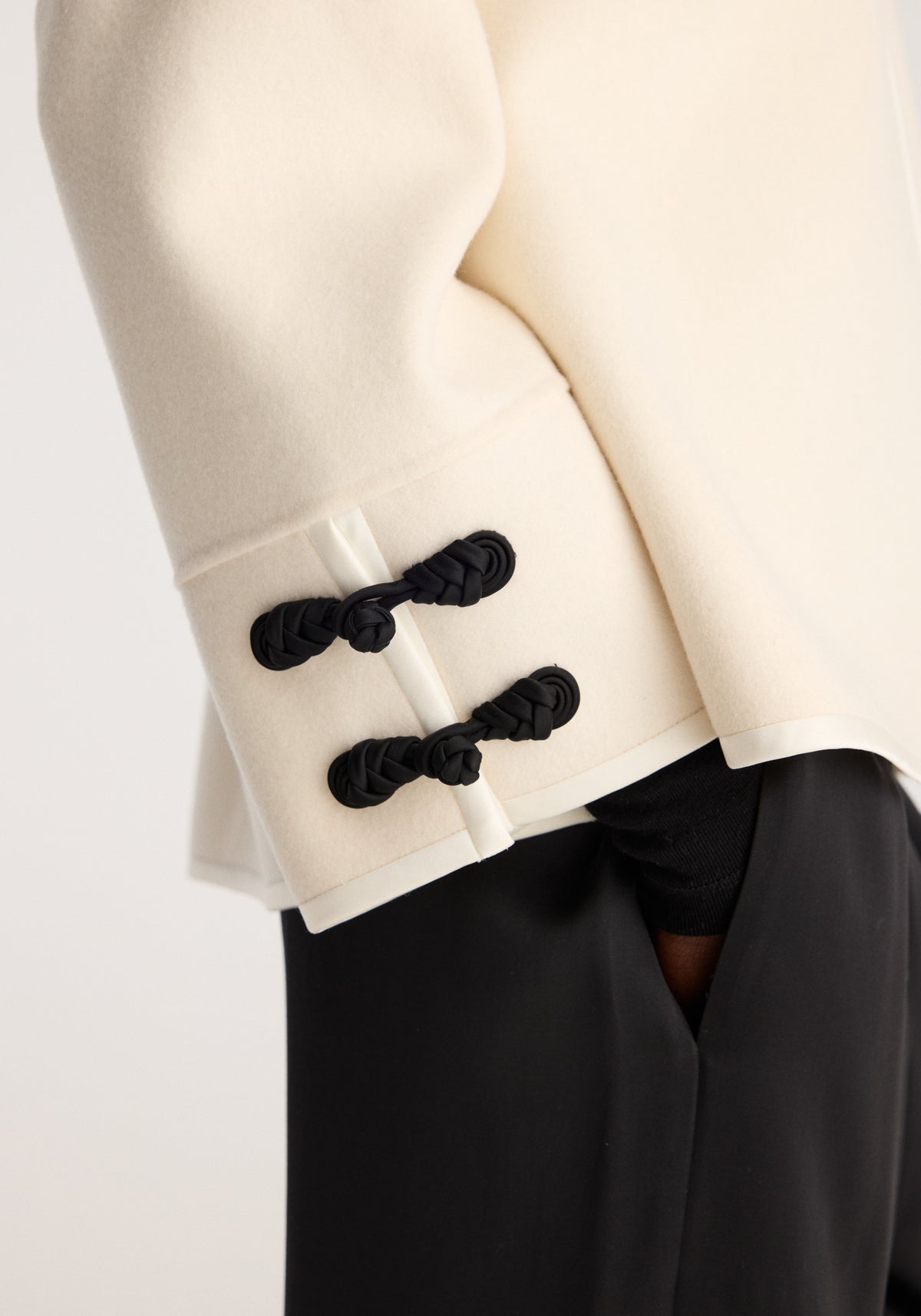 Double-faced pankou jacket | off white with black braided pankou closures at the sleeve and side, shown over black trousers