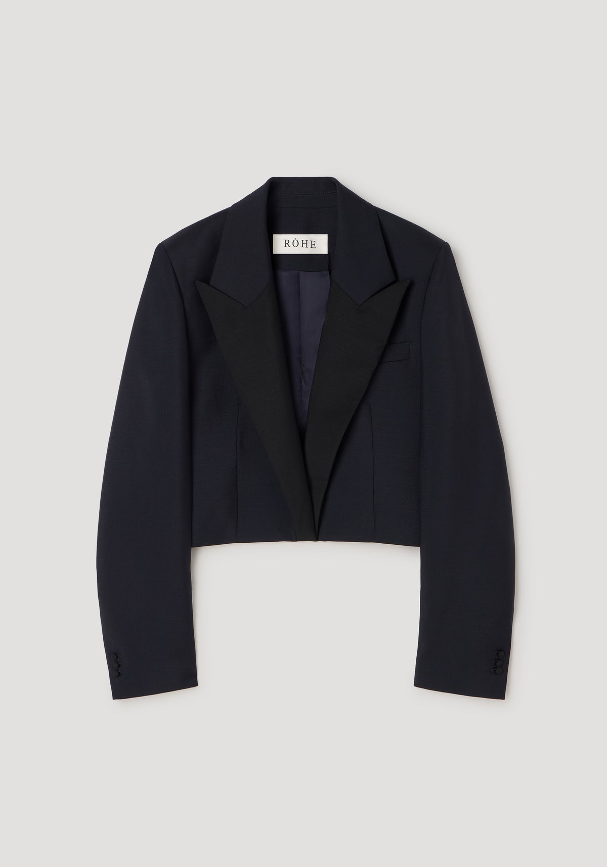 Cropped blazer | navy displayed flat with long sleeves, structured shoulders, and a contrasting black lapel collar on a light gray background.
