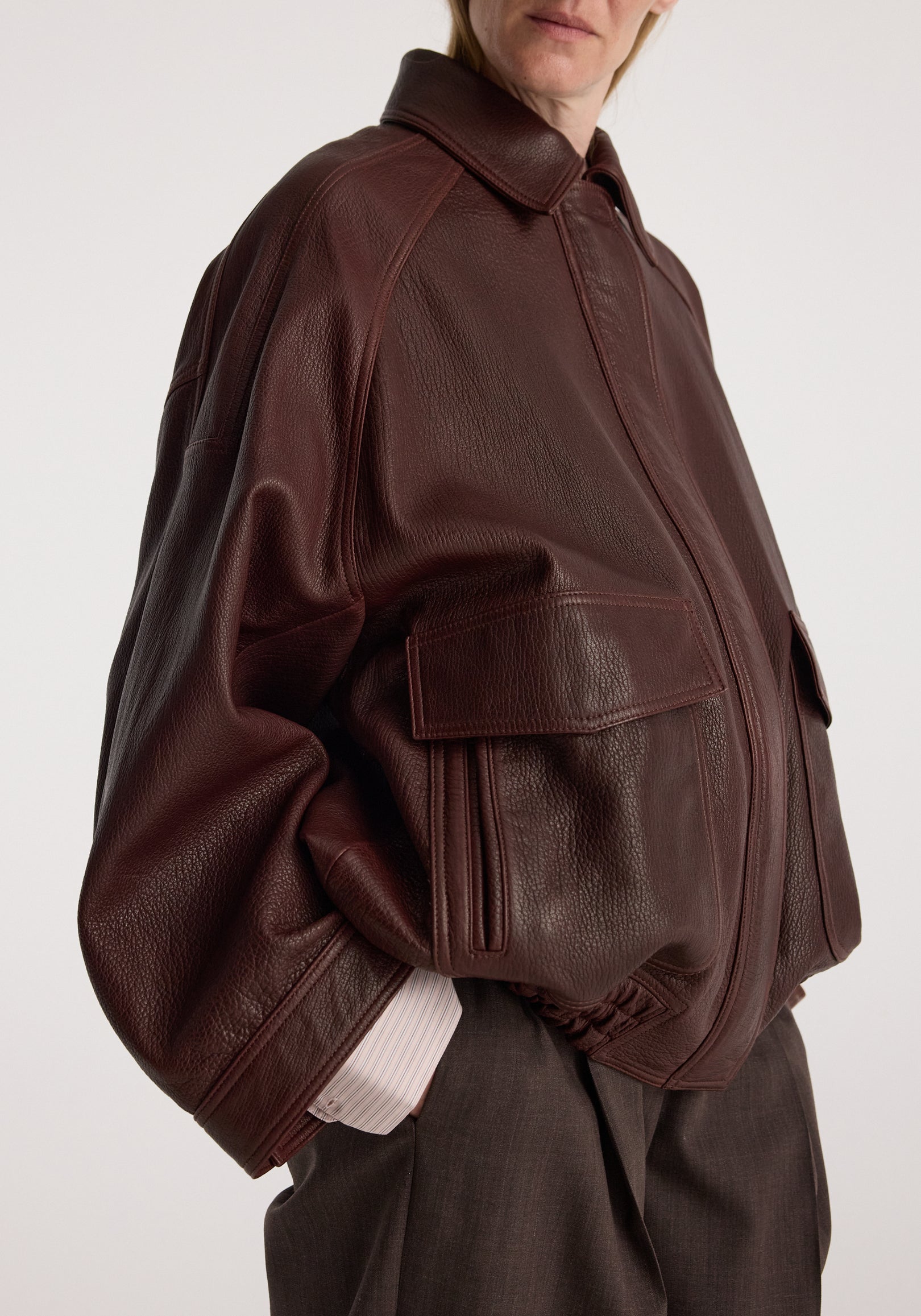 Grain leather aviator jacket | chestnut in textured brown leather with a front zip, oversized collar, roomy pockets, and ribbed cuffs on a model