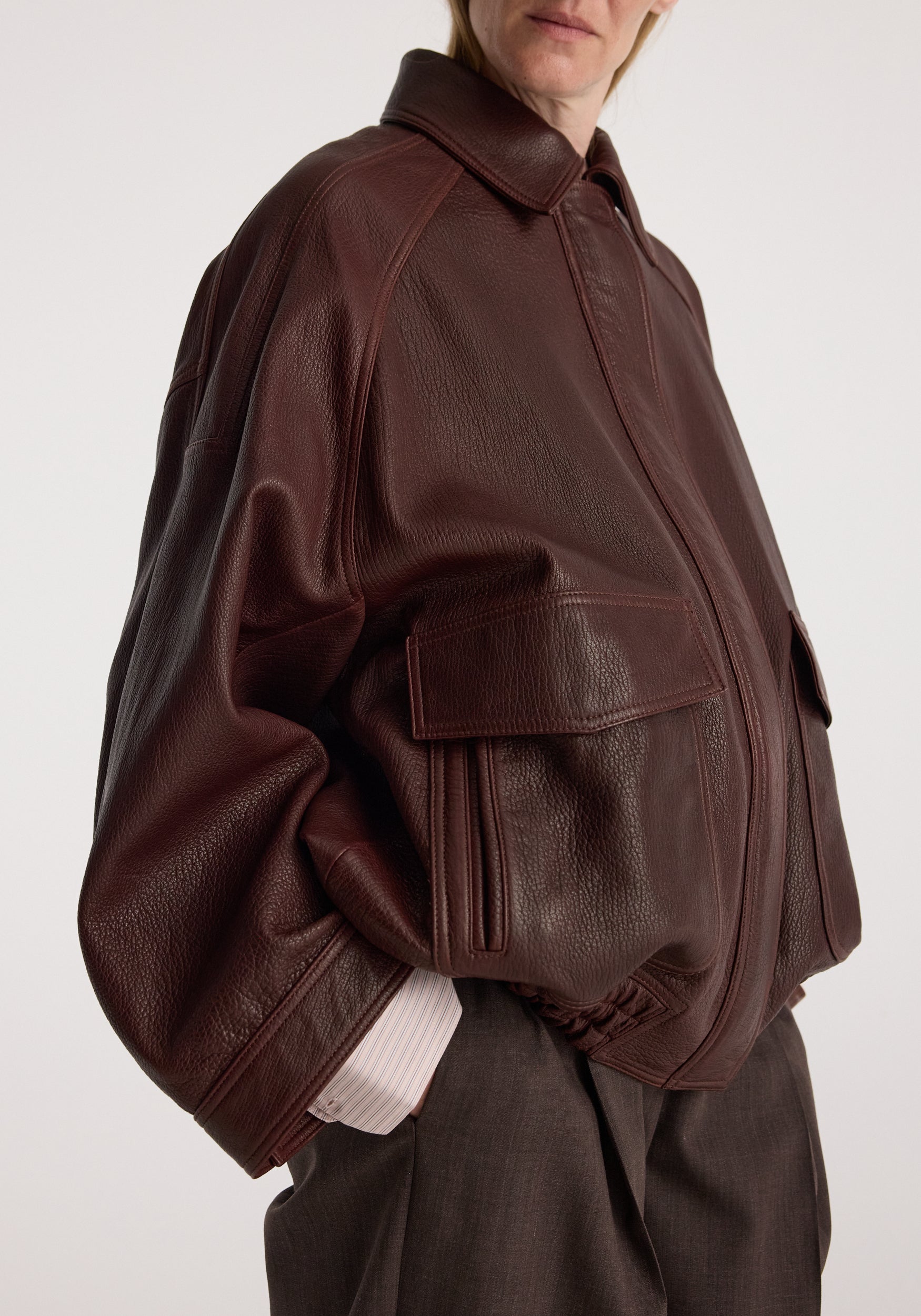 Grain leather aviator jacket | chestnut in textured brown leather with a front zip, oversized collar, roomy pockets, and ribbed cuffs on a model