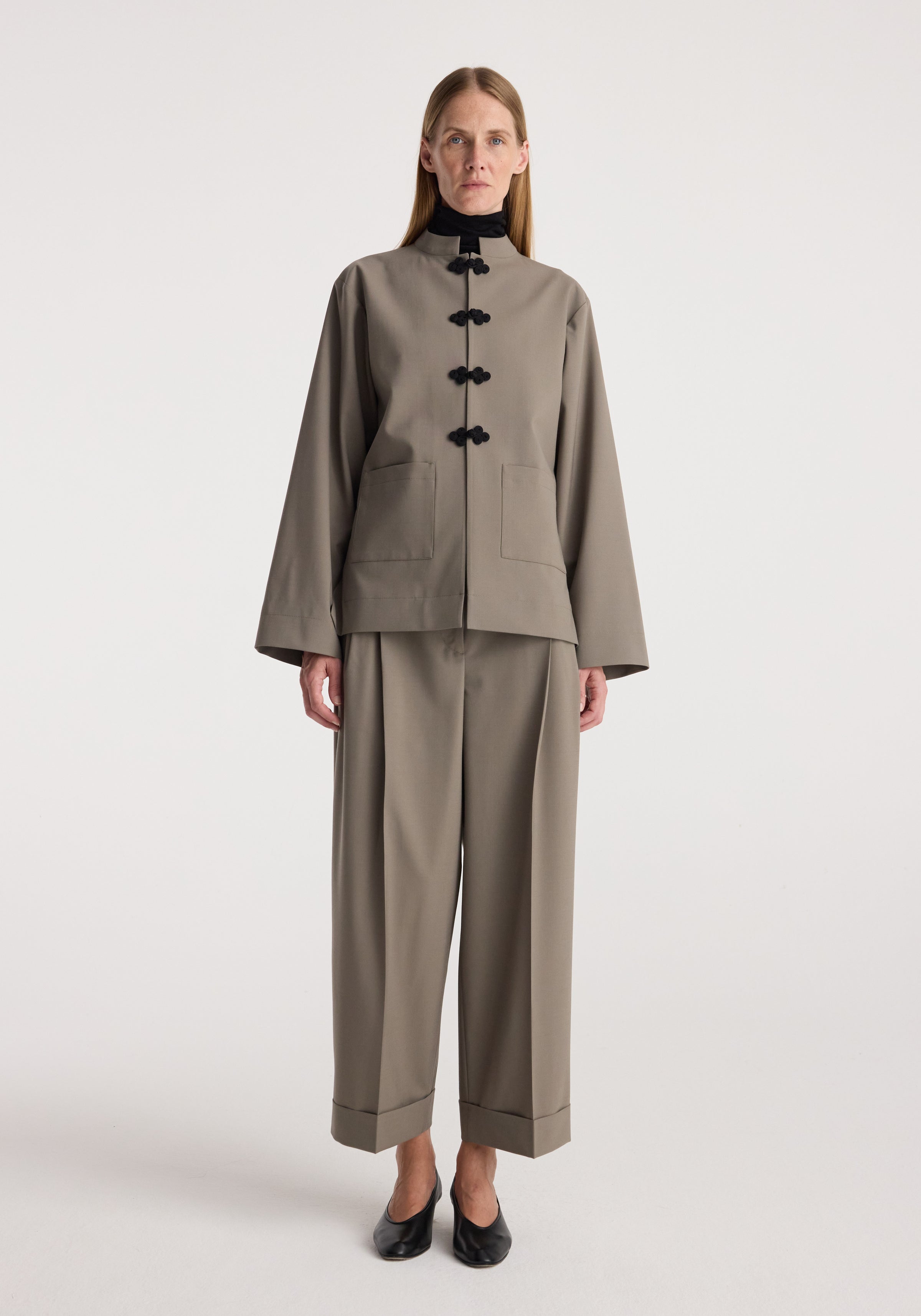 Pankou closure jacket | taupe worn by a model with matching taupe trousers, black shoes, front pockets, and traditional pankou fastenings