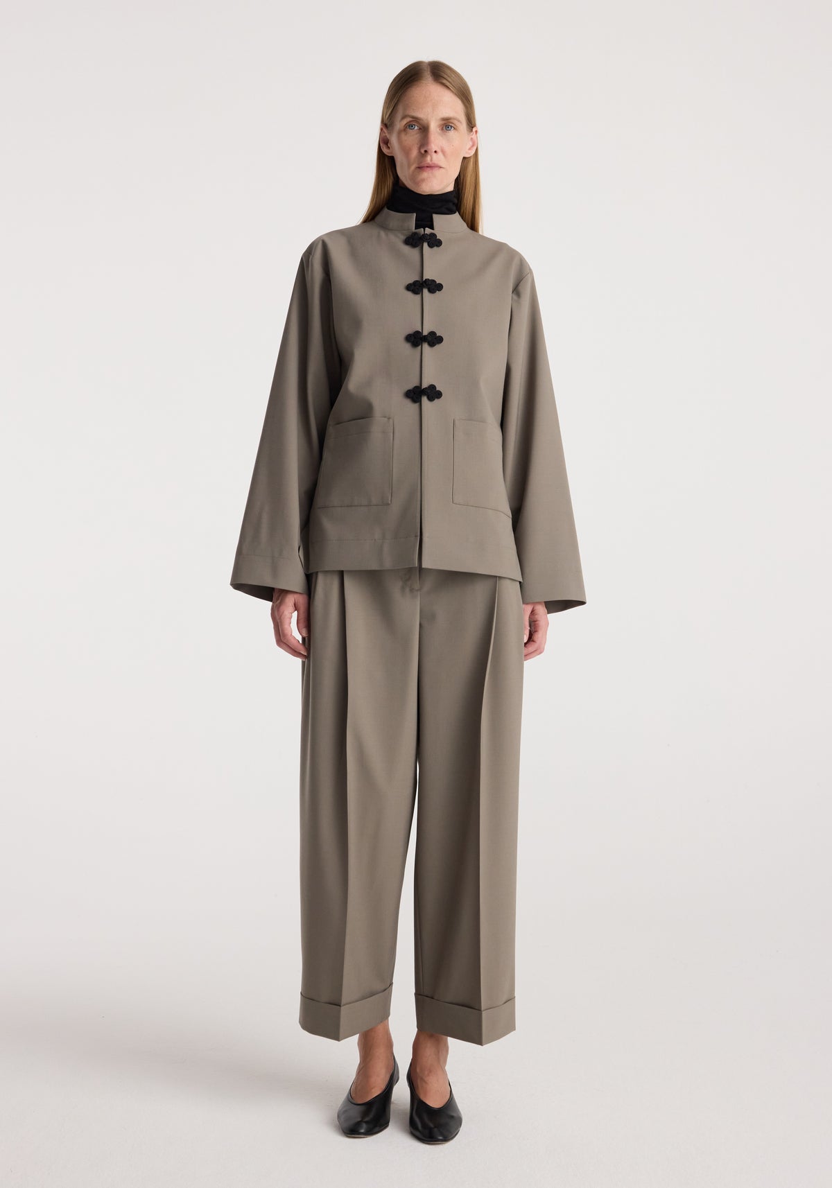 Pankou closure jacket | taupe worn by a model with matching taupe trousers, black shoes, front pockets, and traditional pankou fastenings