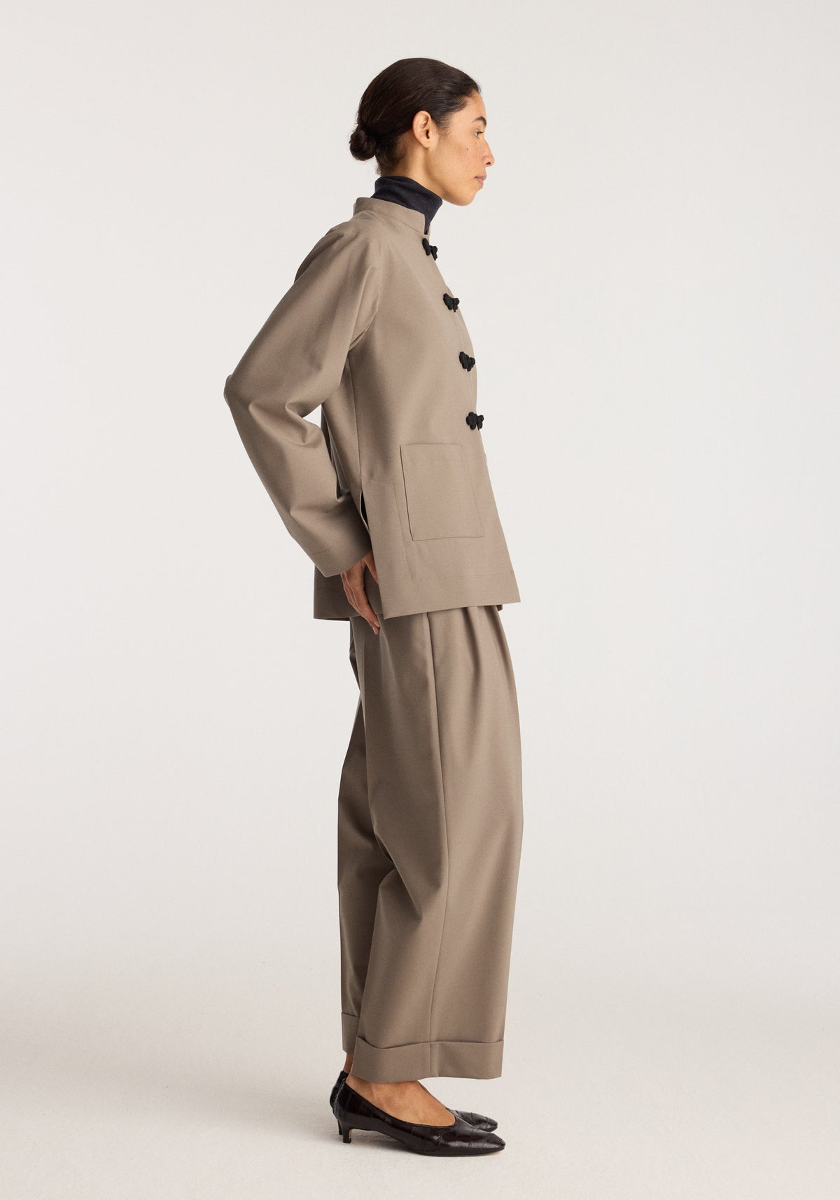 Pankou closure jacket | taupe shown on a model in side profile with a high collar and dark pankou closures