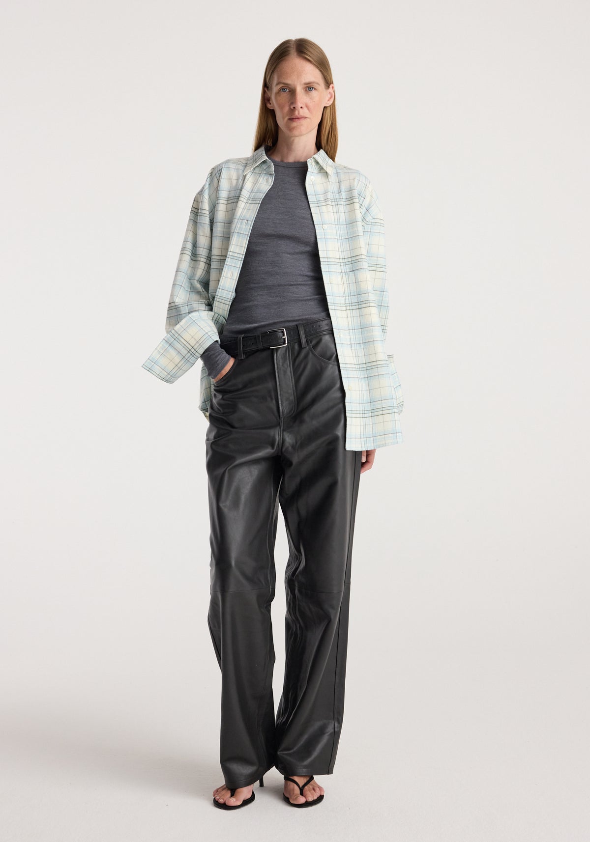 Flannel check overshirt | sea green check worn open over a dark top, styled with black leather trousers and sandals on a model in a studio setting
