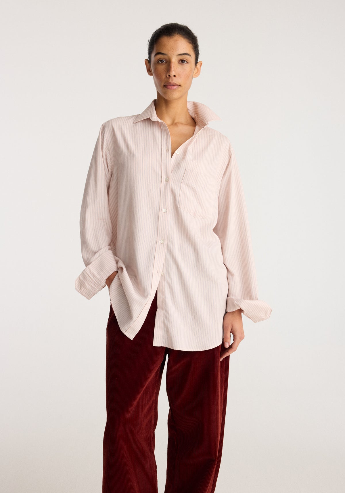 Classic fit striped shirt | rose stripe worn by a model with a relaxed fit long sleeve design and button front in pale pink stripes.