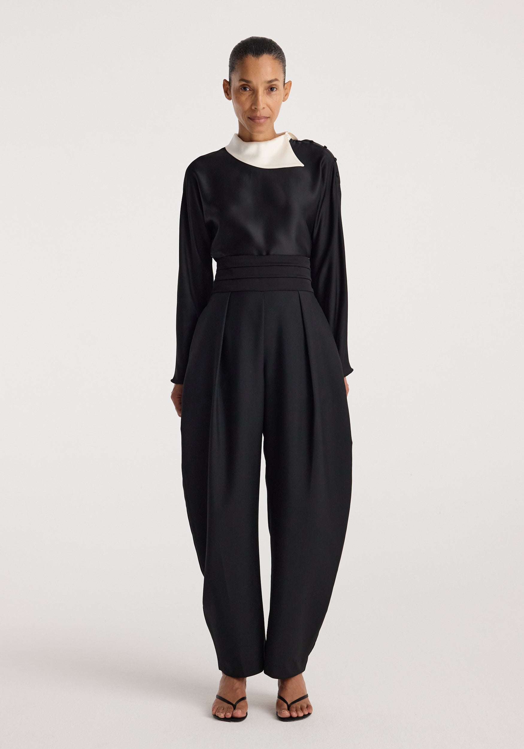 Model wearing Reimagined collar top | black, a black long sleeve top with a contrasting white collar, styled with wide leg trousers and sandals