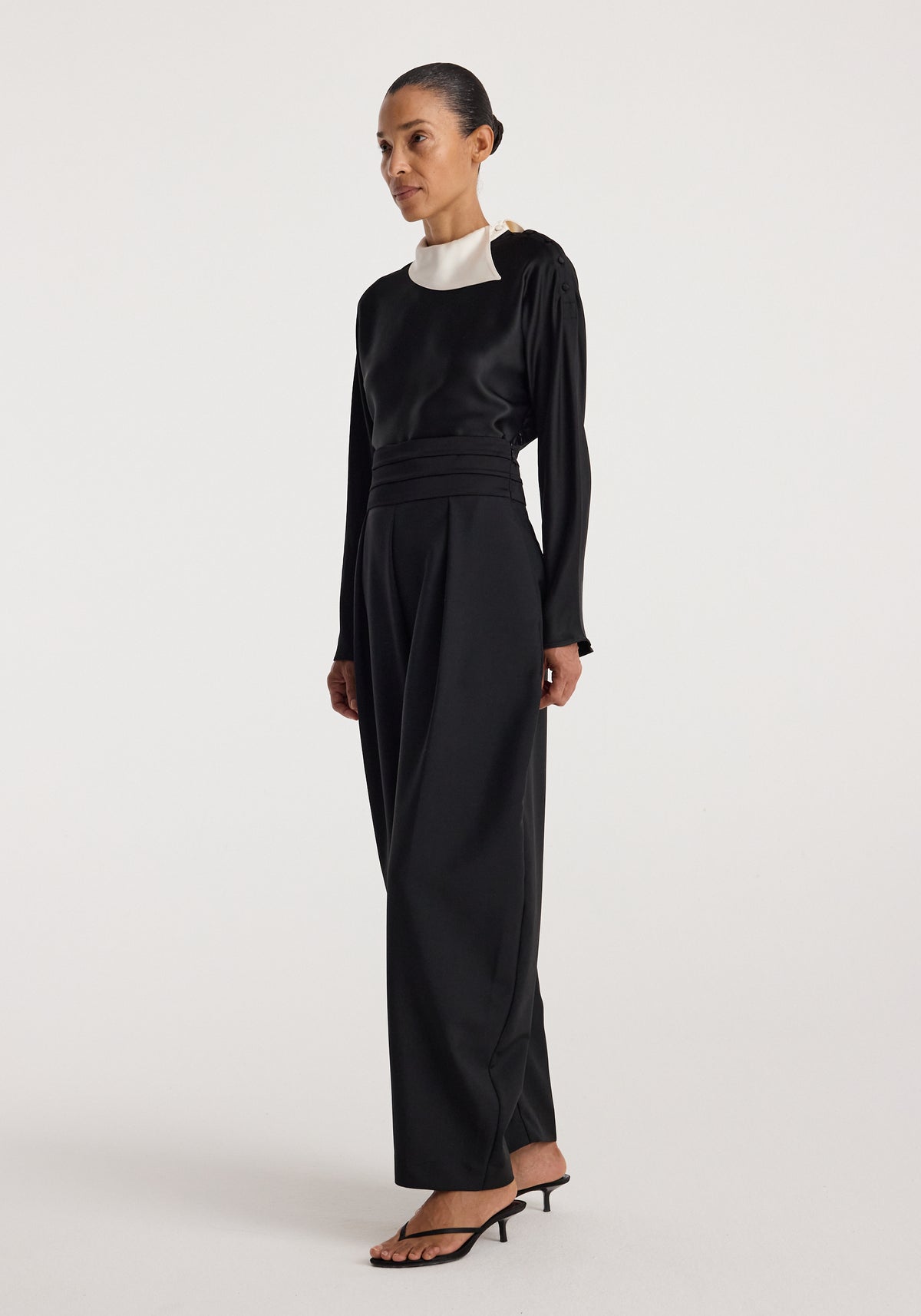 Model wearing Reimagined collar top | black, a long sleeve black top with a contrasting white collar, paired with black trousers and heeled sandals
