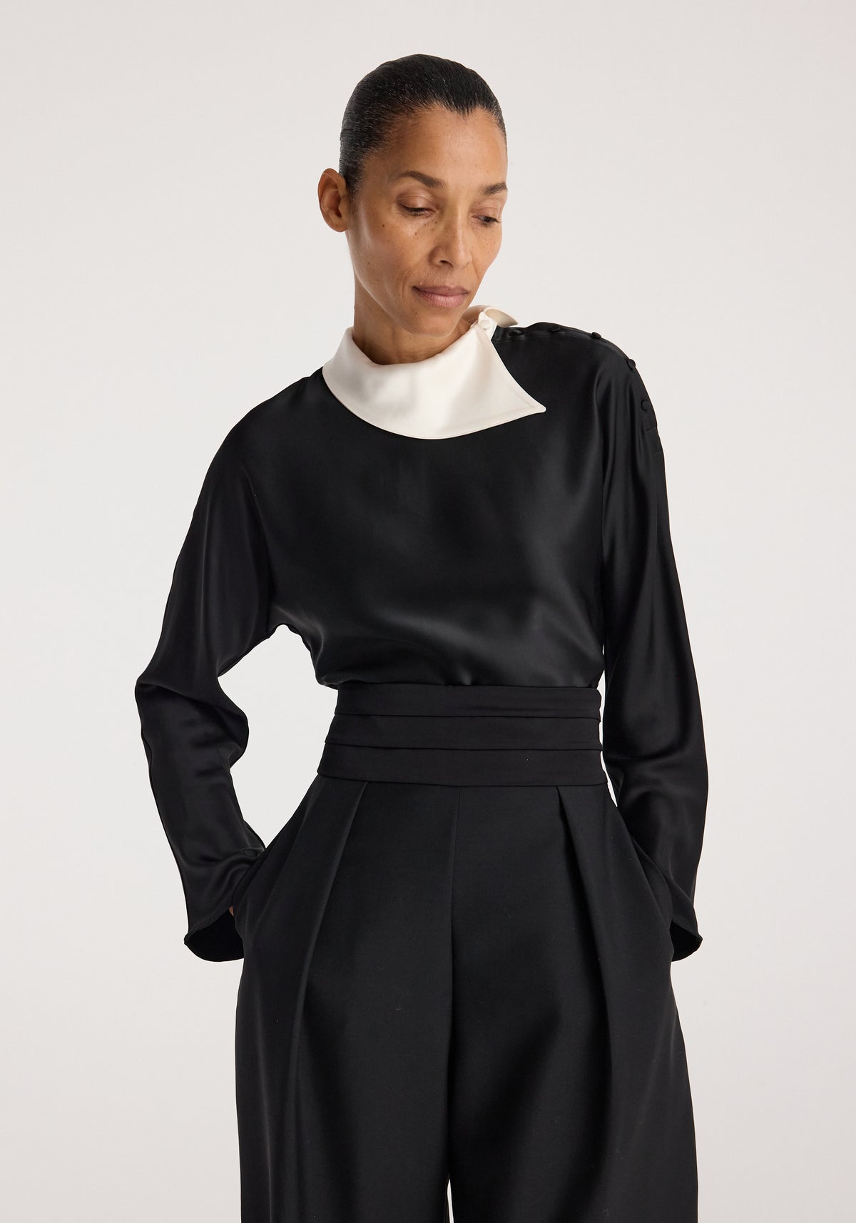 Reimagined collar top | black worn by a model, featuring long sleeves, a sculptural white contrasting collar, and a fitted waist in smooth black fabric
