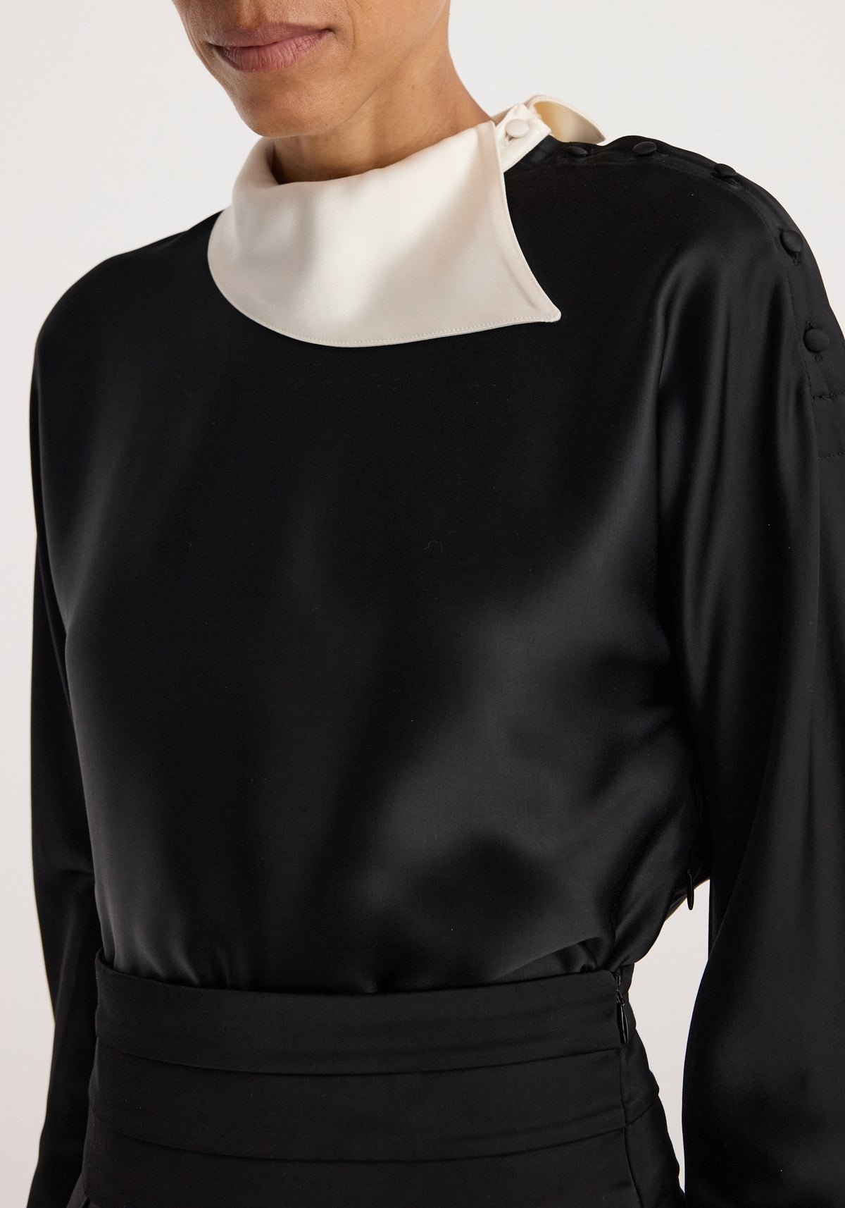 Reimagined collar top | black shown on a model, featuring a sculptural white collar, long sleeves, gathered waist, and smooth black fabric
