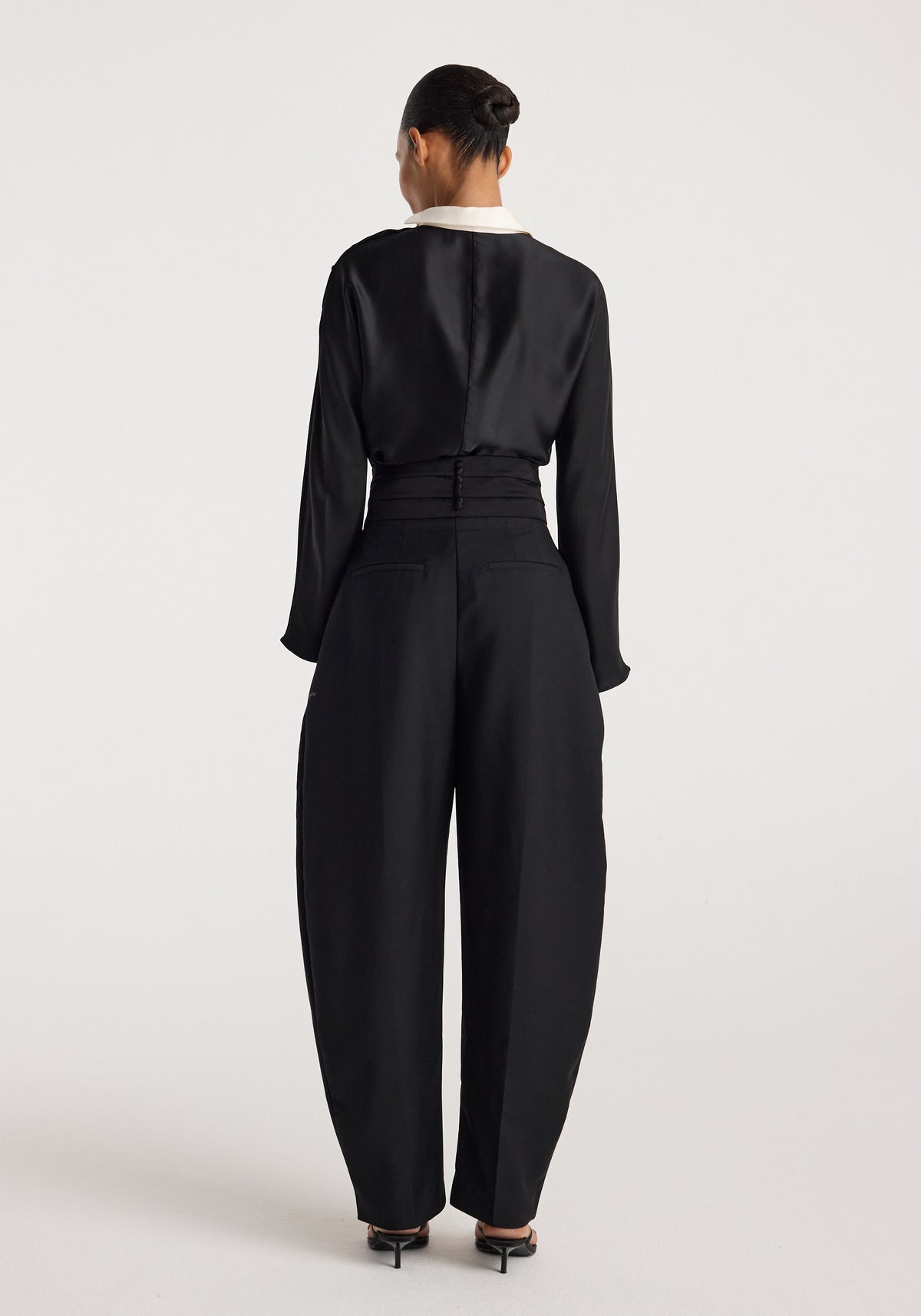 Reimagined collar top | black shown from the back on a model, featuring long sleeves and a contrasting white collar styled with high waisted black trousers
