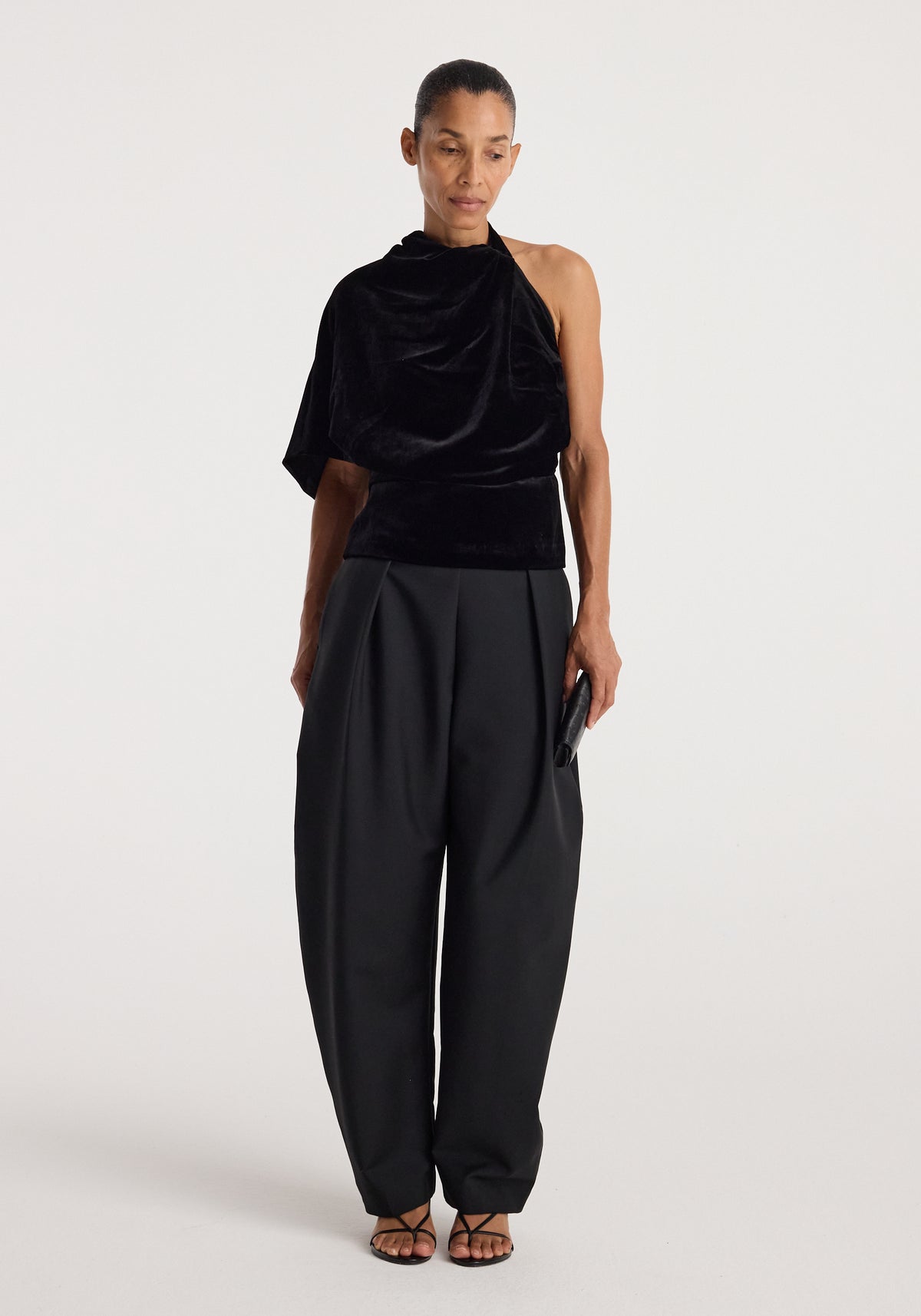 Model wearing the Draped open back silk velvet top | black with voluminous black trousers and strappy sandals against a neutral studio backdrop