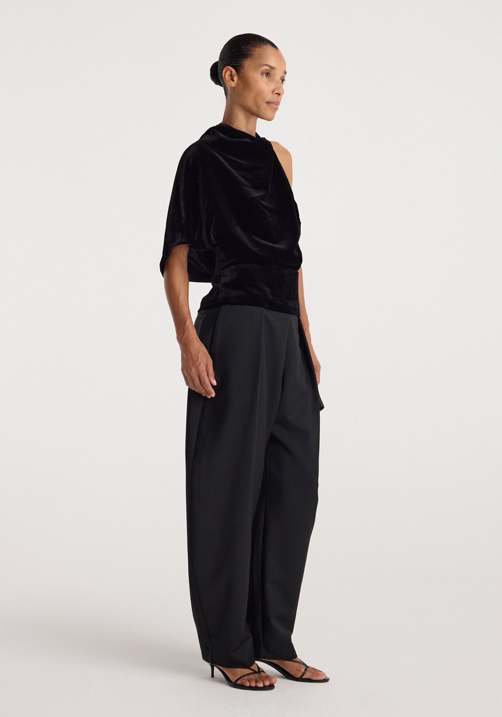 Draped open back silk velvet top | black worn with black wide leg trousers and strappy sandals by a model against a neutral studio background
