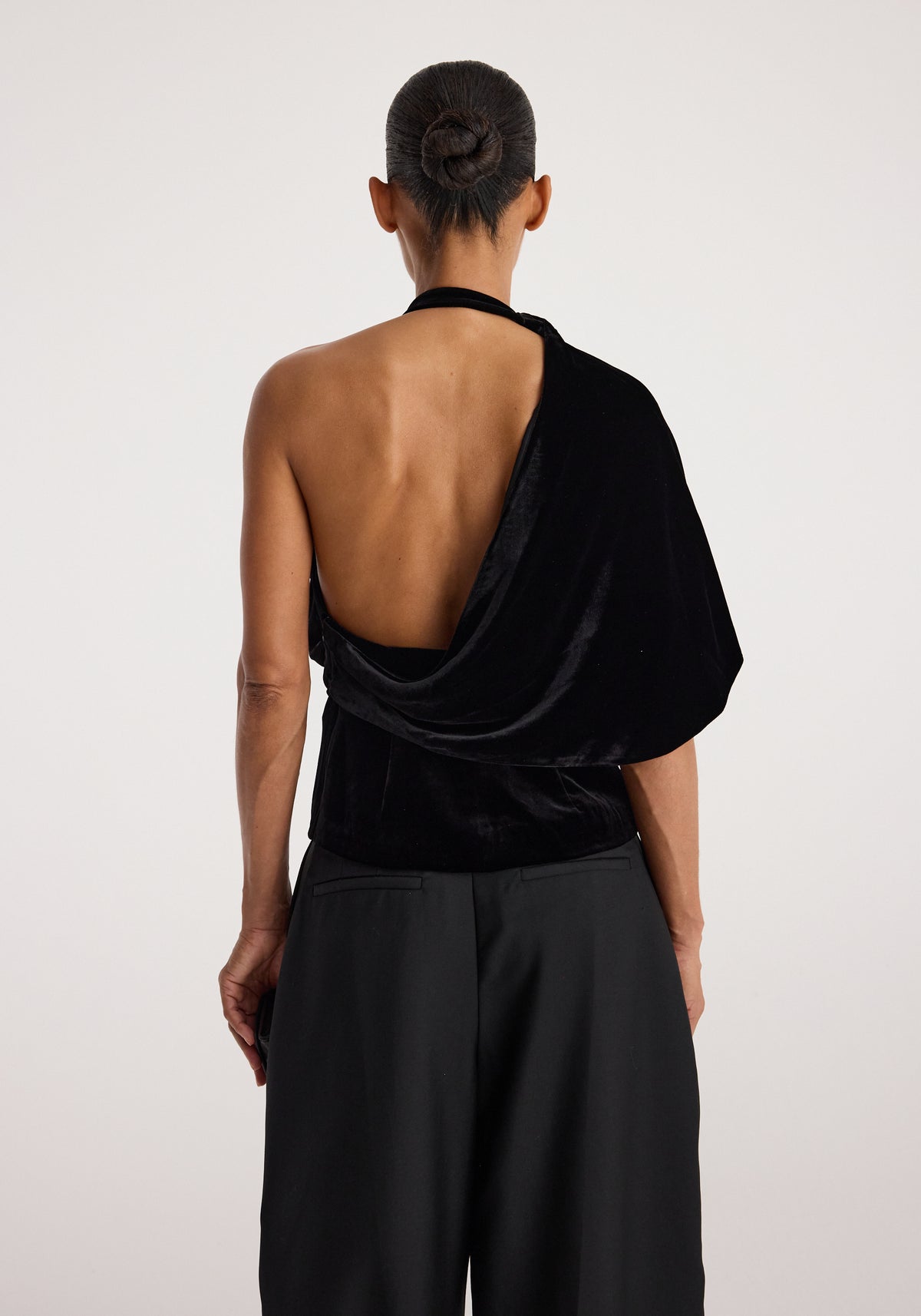 Draped open back silk velvet top | black shown from the back on a model, featuring a low open back, draped neckline, and asymmetrical black velvet silhouette