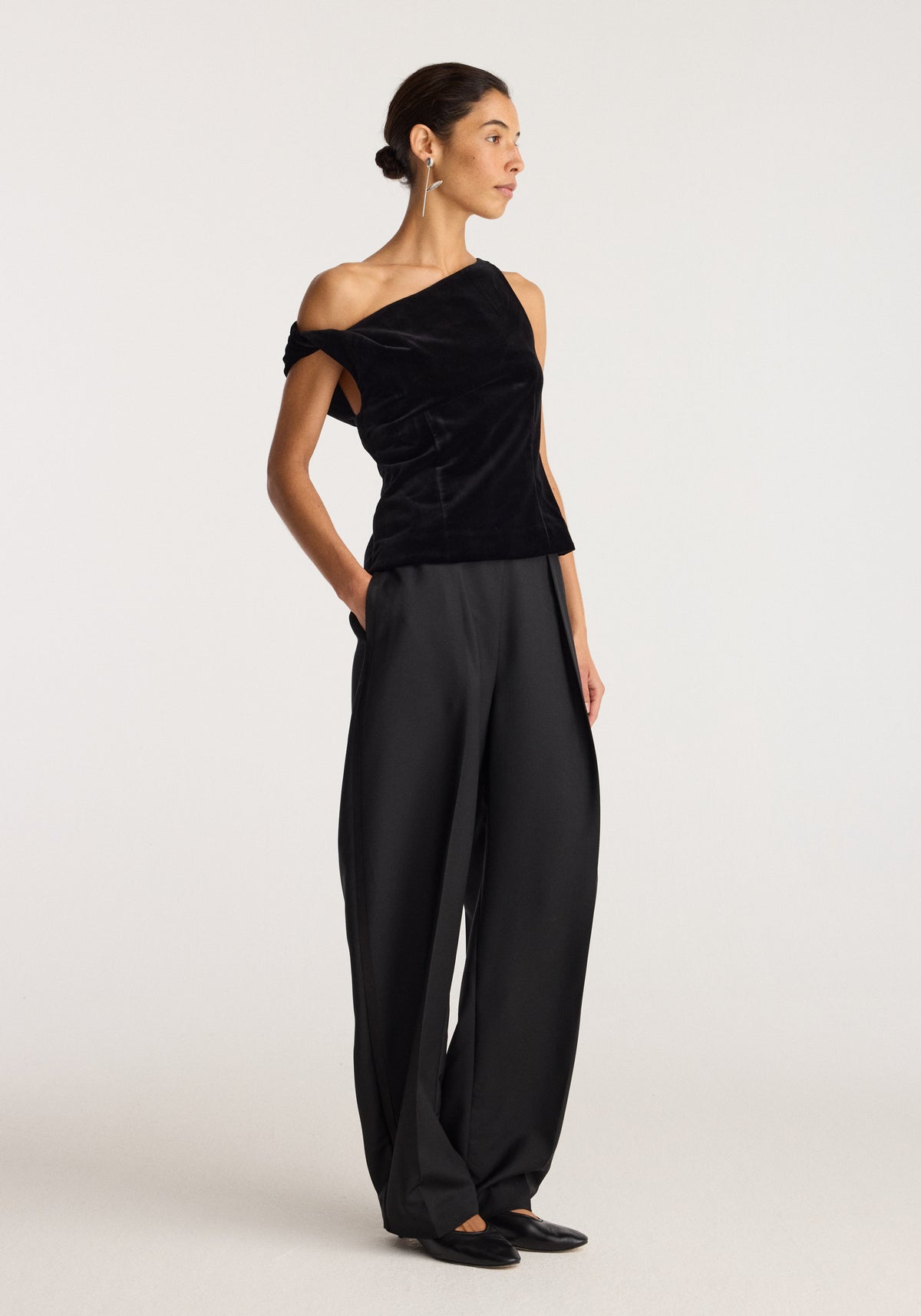 Tulip silver earring (single) | silver worn by a woman in a black asymmetrical top and wide leg trousers posing against a light background