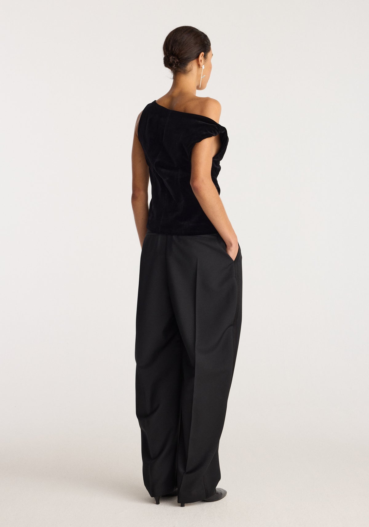 Draped velvet top | black shown from the back on a model, featuring an asymmetrical draped neckline and short sleeves