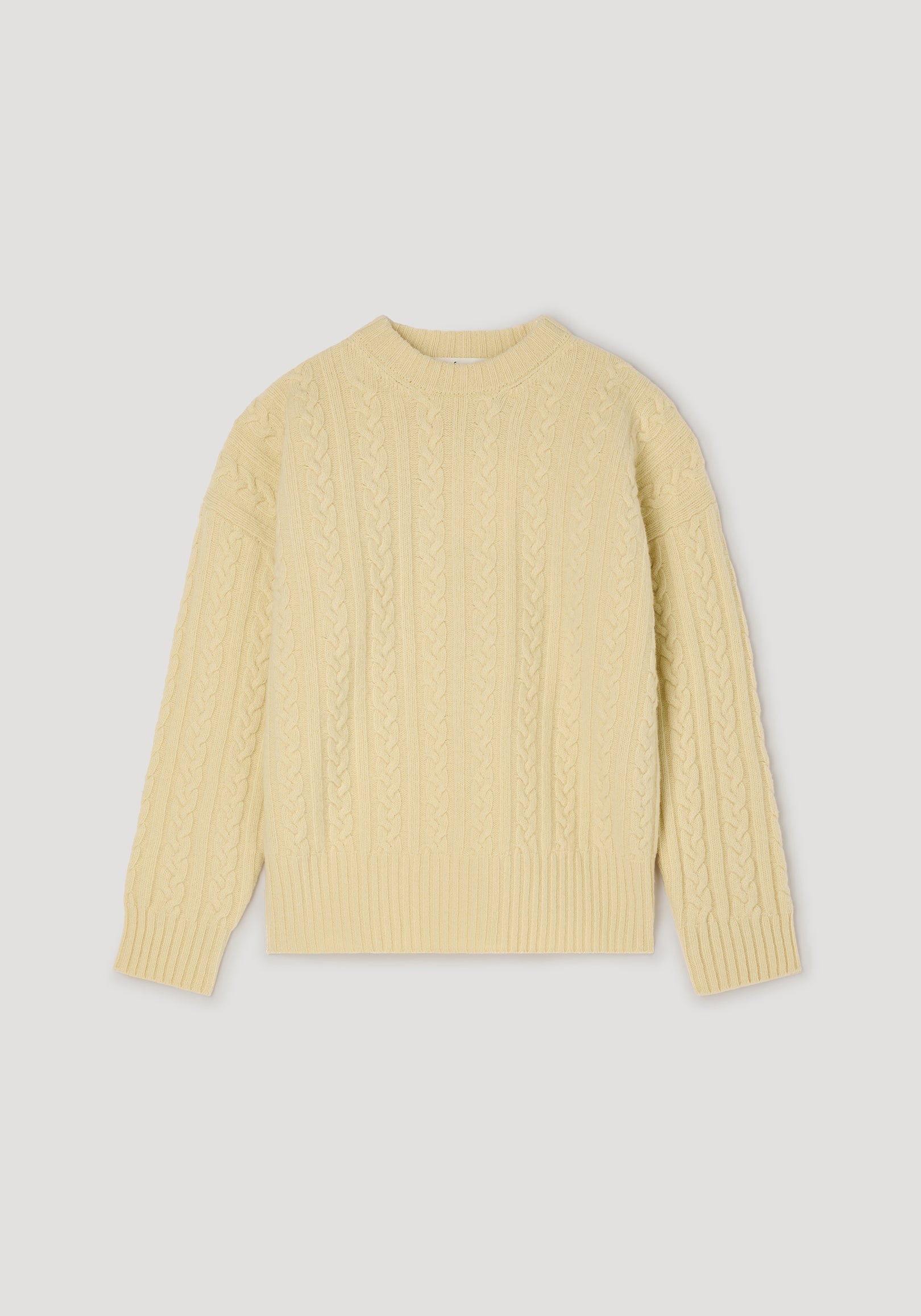 Cable knit jumper | butter in a soft pale yellow color, featuring a classic cable knit pattern with long sleeves and ribbed cuffs and hem for a cozy fit.