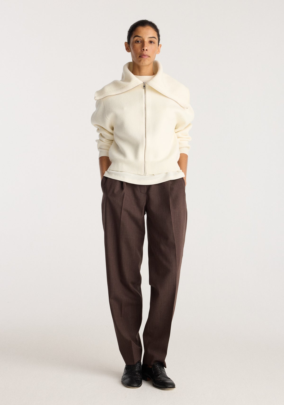 Reversible sailor zip cardigan | cream worn by a model with a front zip and sailor collar paired with brown trousers and black shoes against a neutral backdrop
