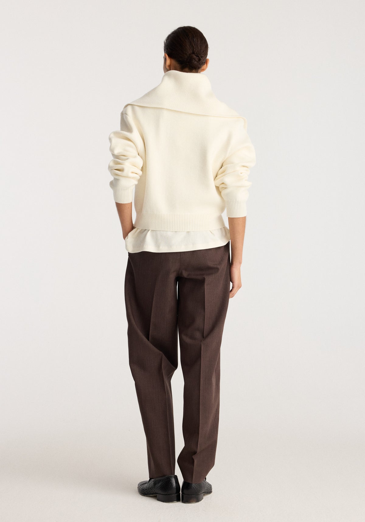 Reversible sailor zip cardigan | cream shown from the back on a model with rolled sleeves, high collar, relaxed fit, brown trousers, and black shoes
