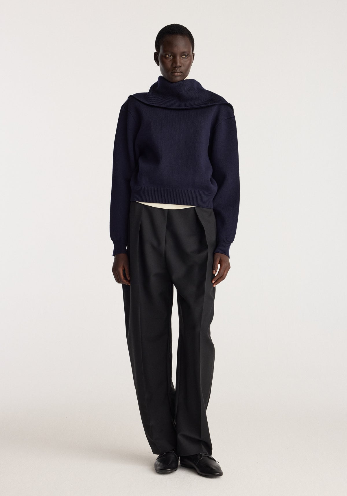Model wearing Reversible sailor zip cardigan | navy with black trousers in a studio setting