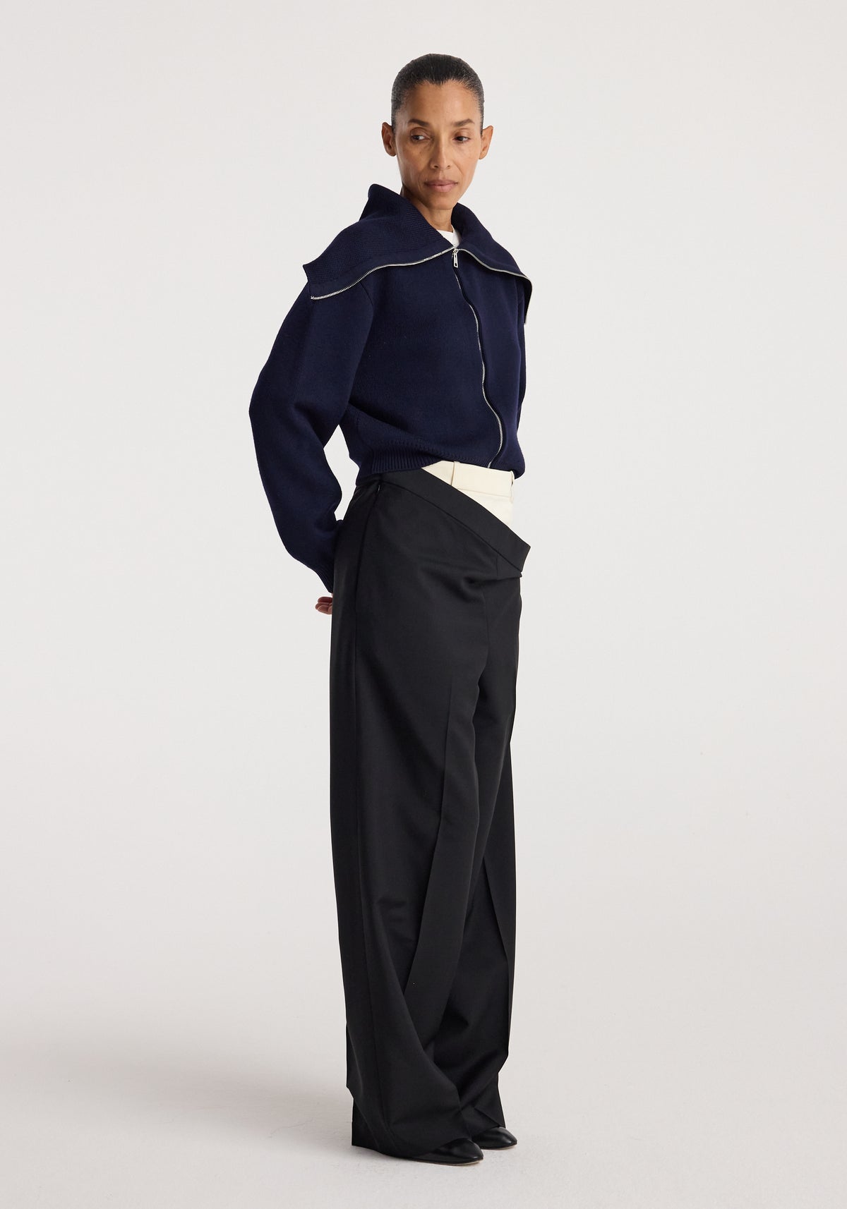 Model wearing a navy Two way sailor zip cardigan with a front zipper and sailor collar paired with high-waisted black wide-leg trousers, standing against a plain background.