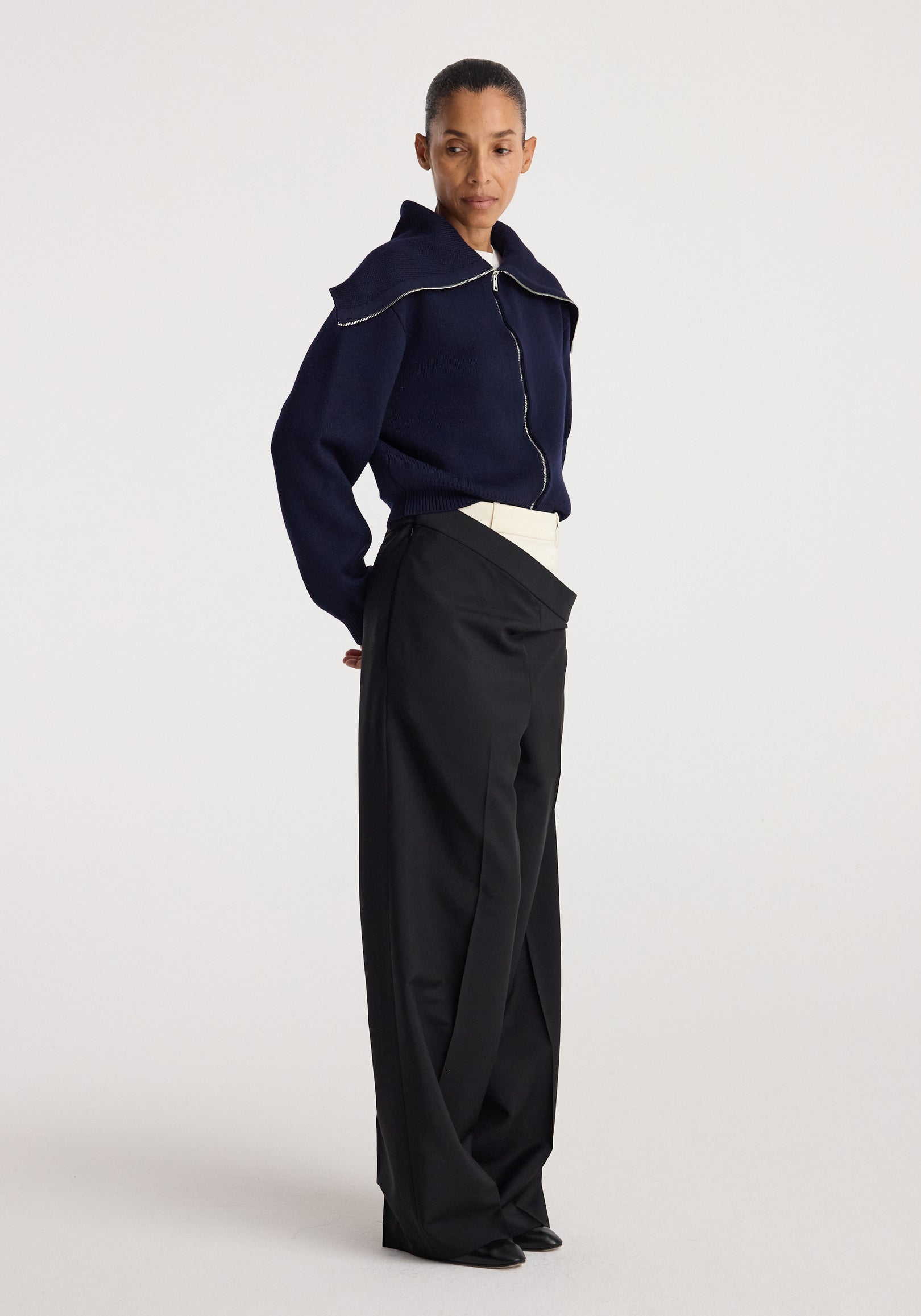Model wearing a navy Two way sailor zip cardigan with a front zipper and sailor collar paired with high-waisted black wide-leg trousers, standing against a plain background.