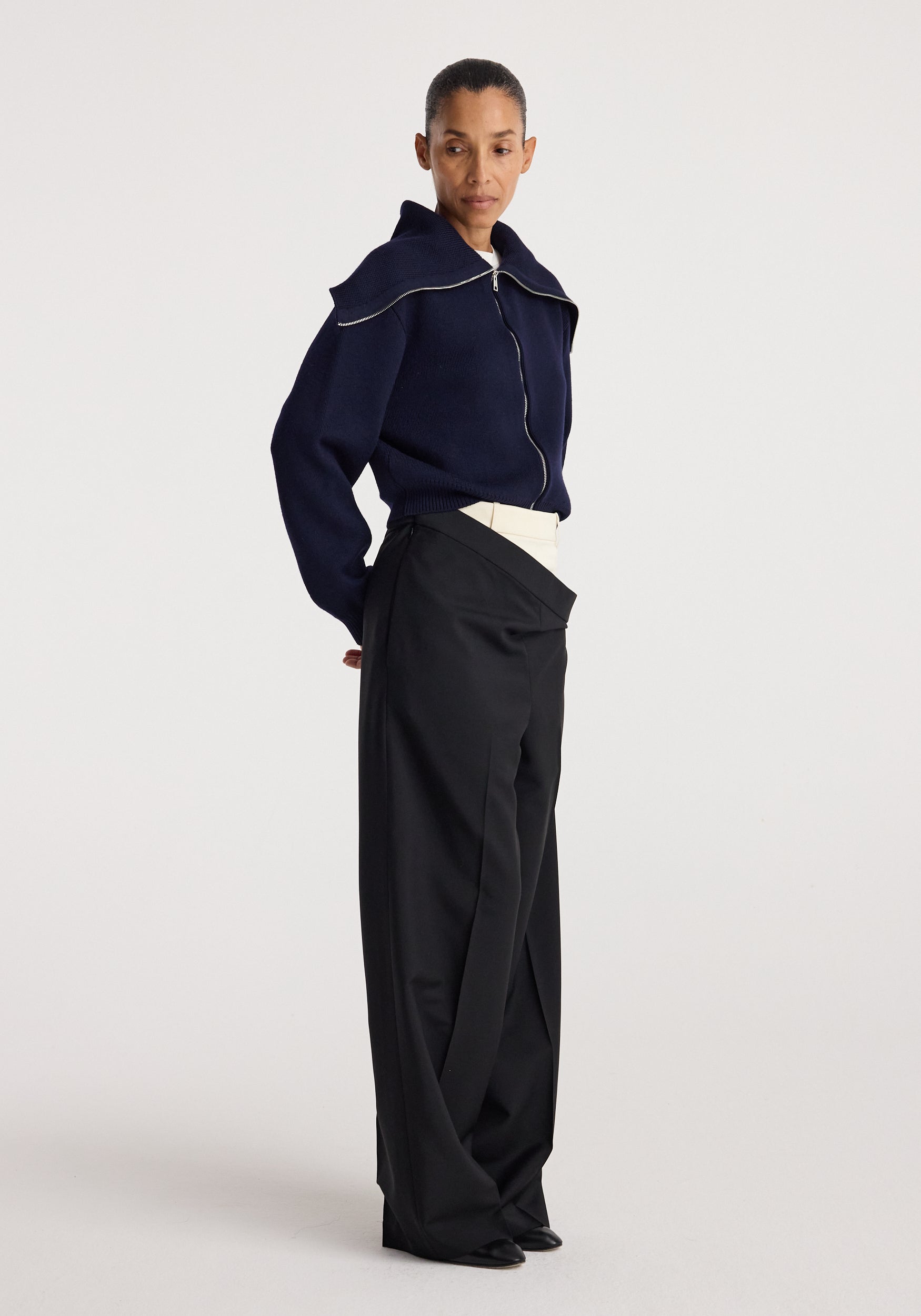 Model wearing a navy Two way sailor zip cardigan with a front zipper and sailor collar paired with high-waisted black wide-leg trousers, standing against a plain background.
