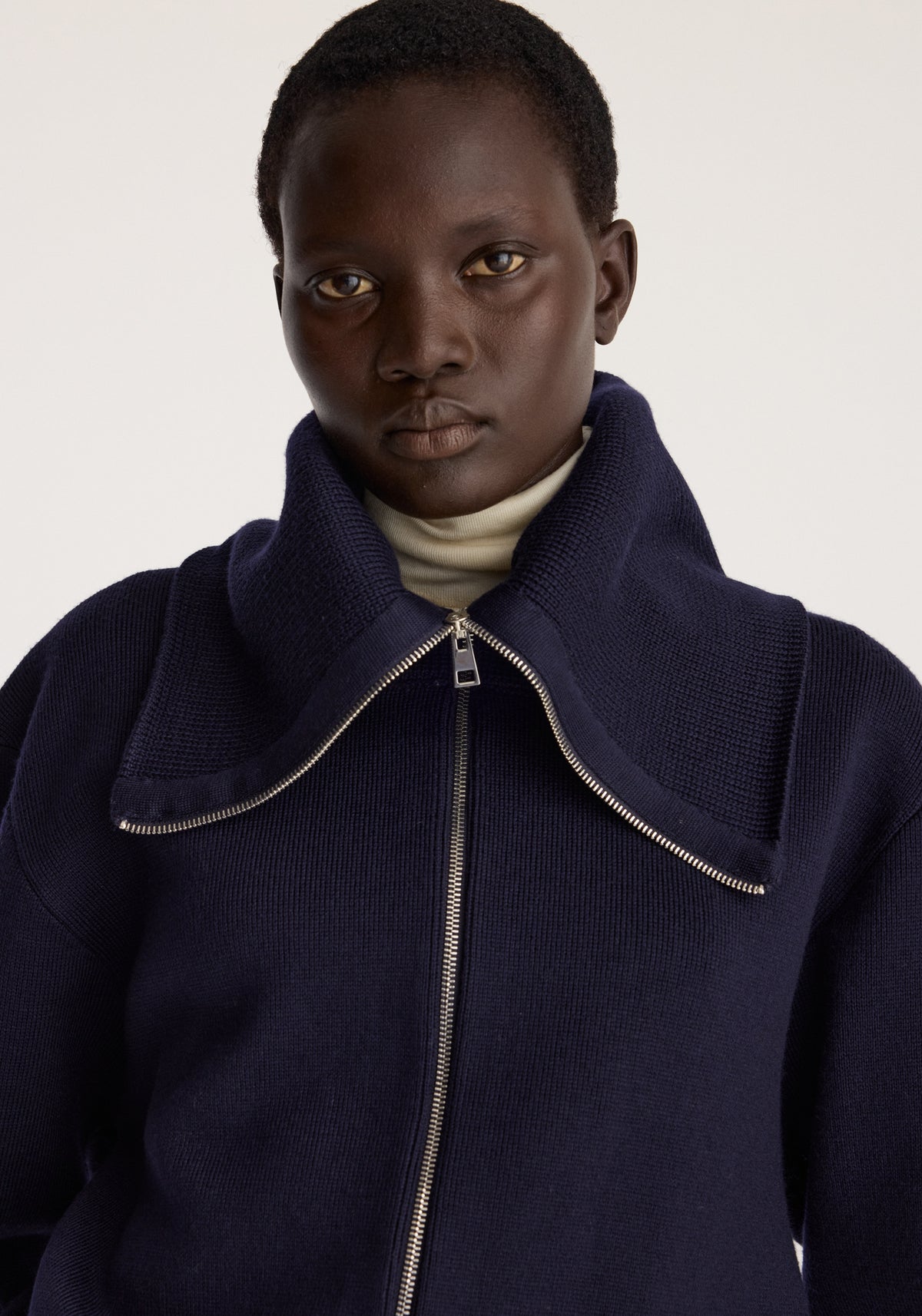 Reversible sailor zip cardigan | navy worn by a model with a high collar curved zipper detail and long sleeves