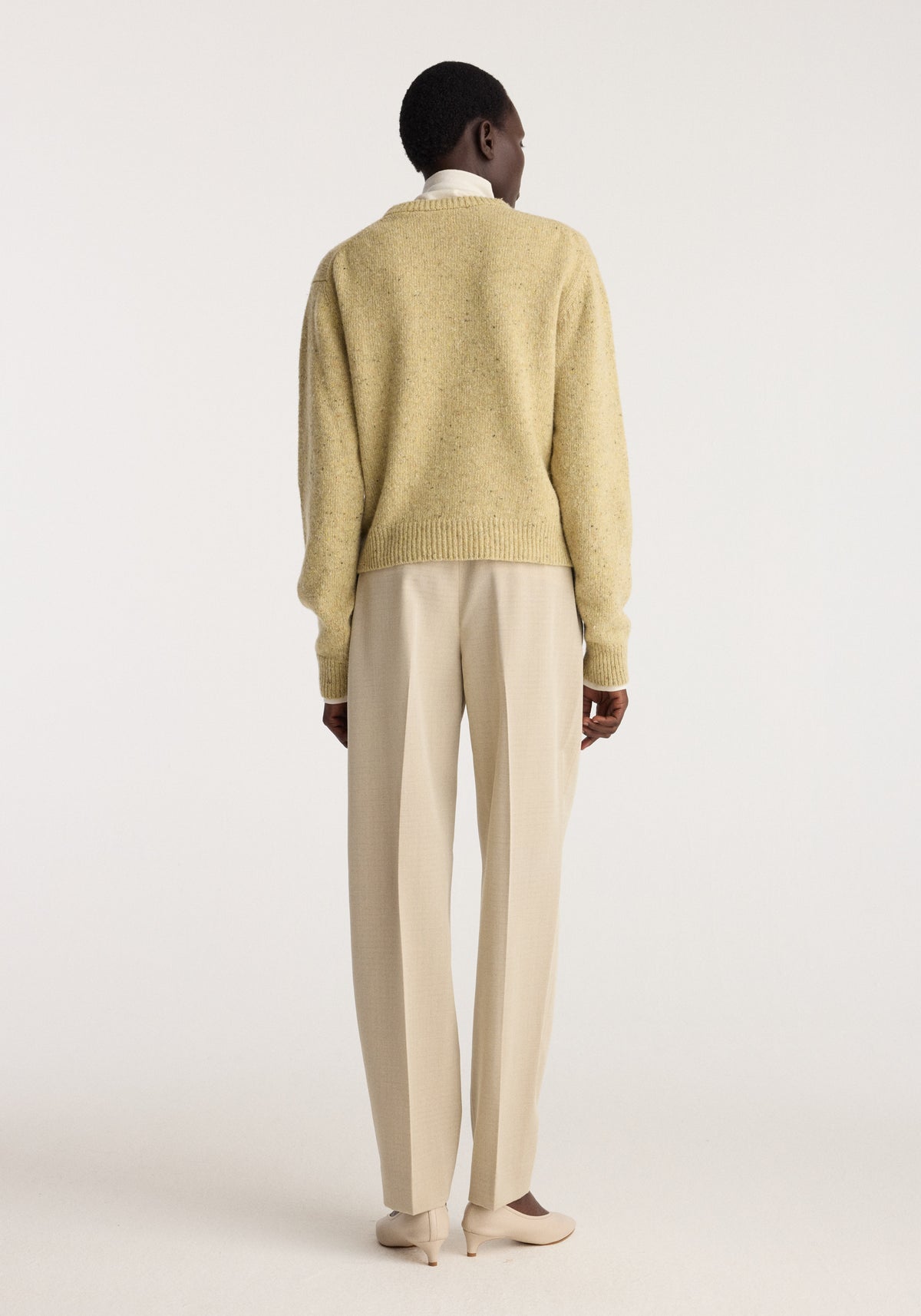 Fitted mouliné crewneck | butter mouliné shown from the back on a model wearing a textured butter yellow sweater with long sleeves and ribbed hem