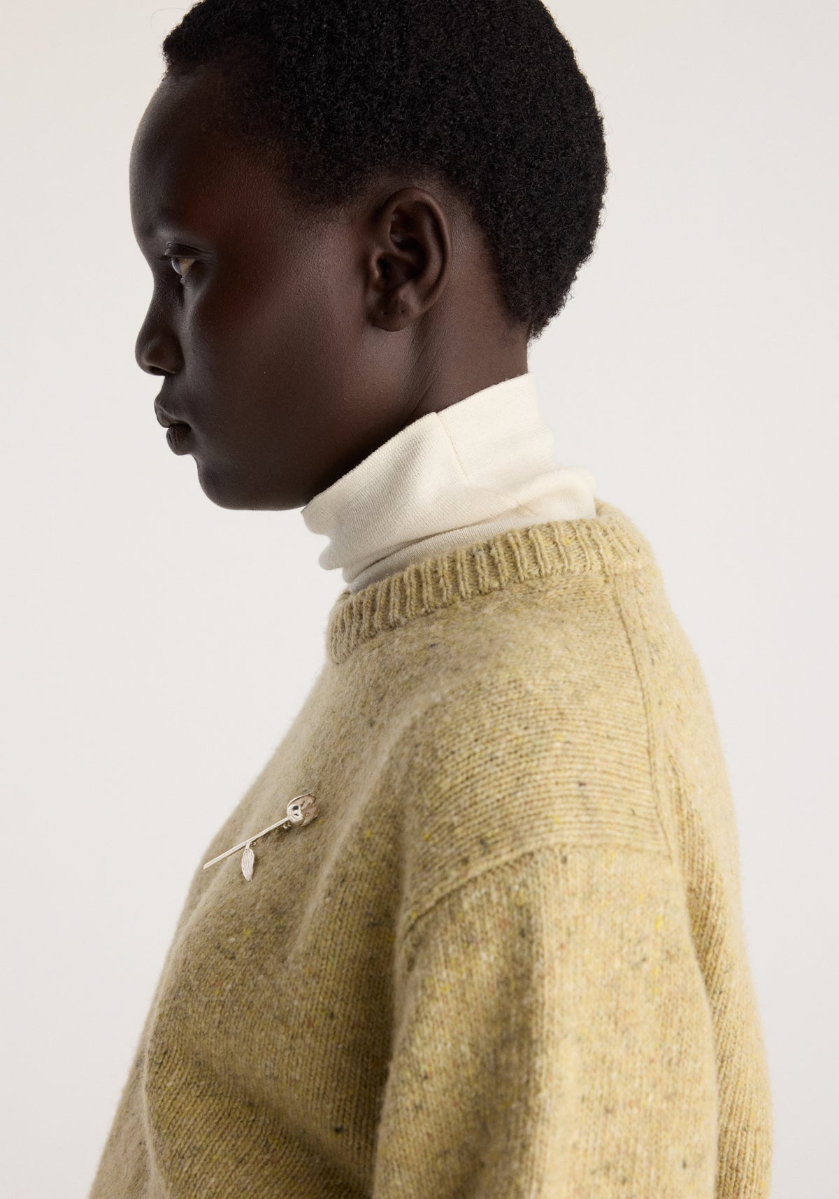 Side profile of a model wearing Fitted mouliné crewneck | butter mouliné in a soft butter yellow knit with textured stitching and long sleeves