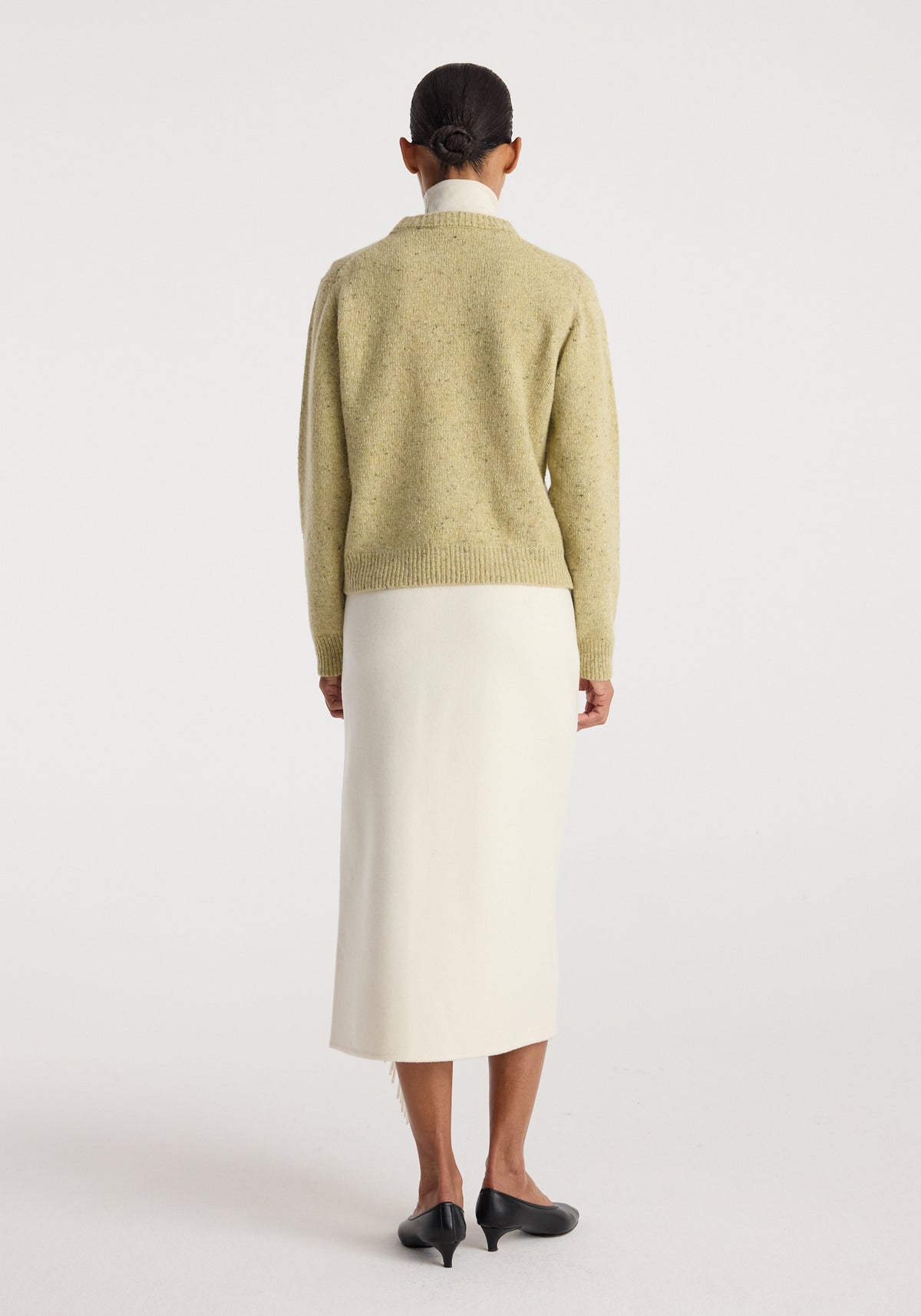 Back view of a model wearing Fitted mouliné crewneck | butter mouliné with a white midi skirt and black heeled shoes in a studio.