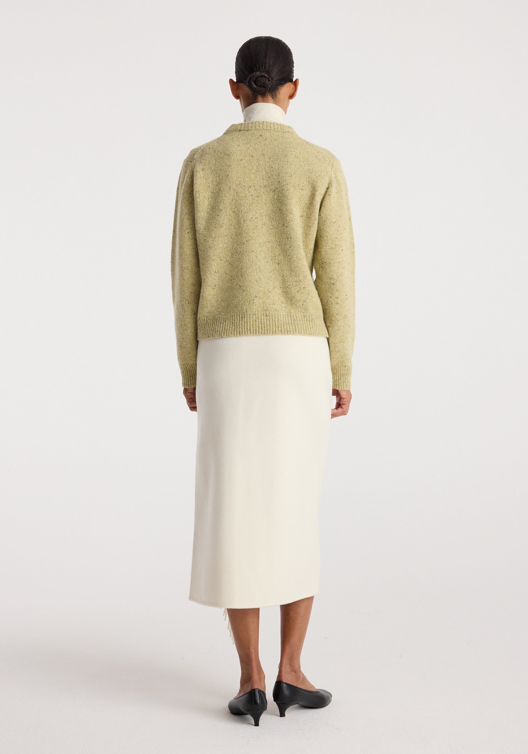 Back view of a model wearing Fitted mouliné crewneck | butter mouliné with a white midi skirt and black heeled shoes in a studio.