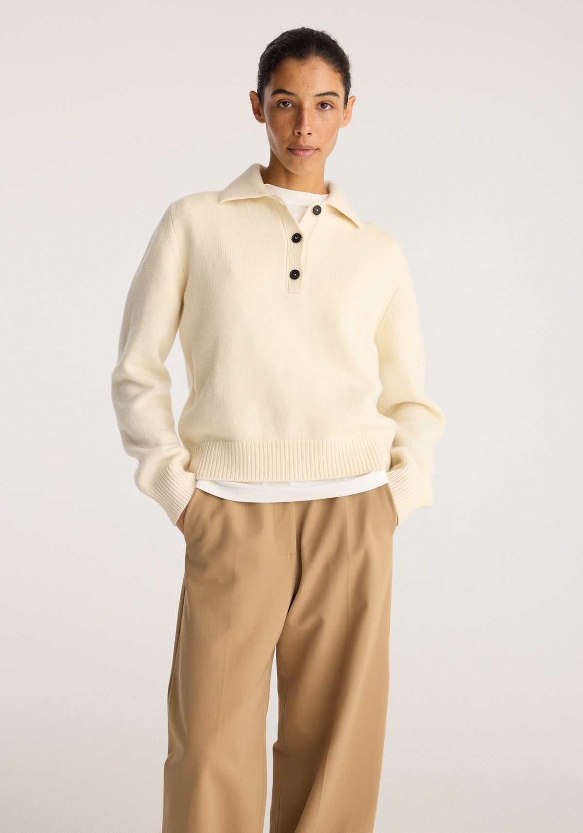 Wool-cashmere polo | cream worn by a model with a collared neckline button placket ribbed cuffs and hem styled with wide leg beige trousers