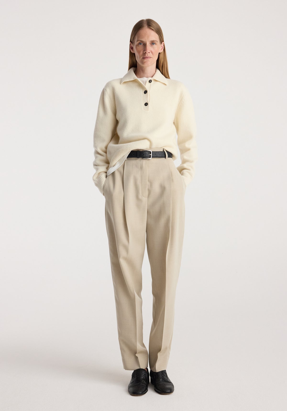 Model wearing Wool-cashmere polo | cream, a cream long sleeve collared knit top styled with beige trousers and black shoes against a neutral background