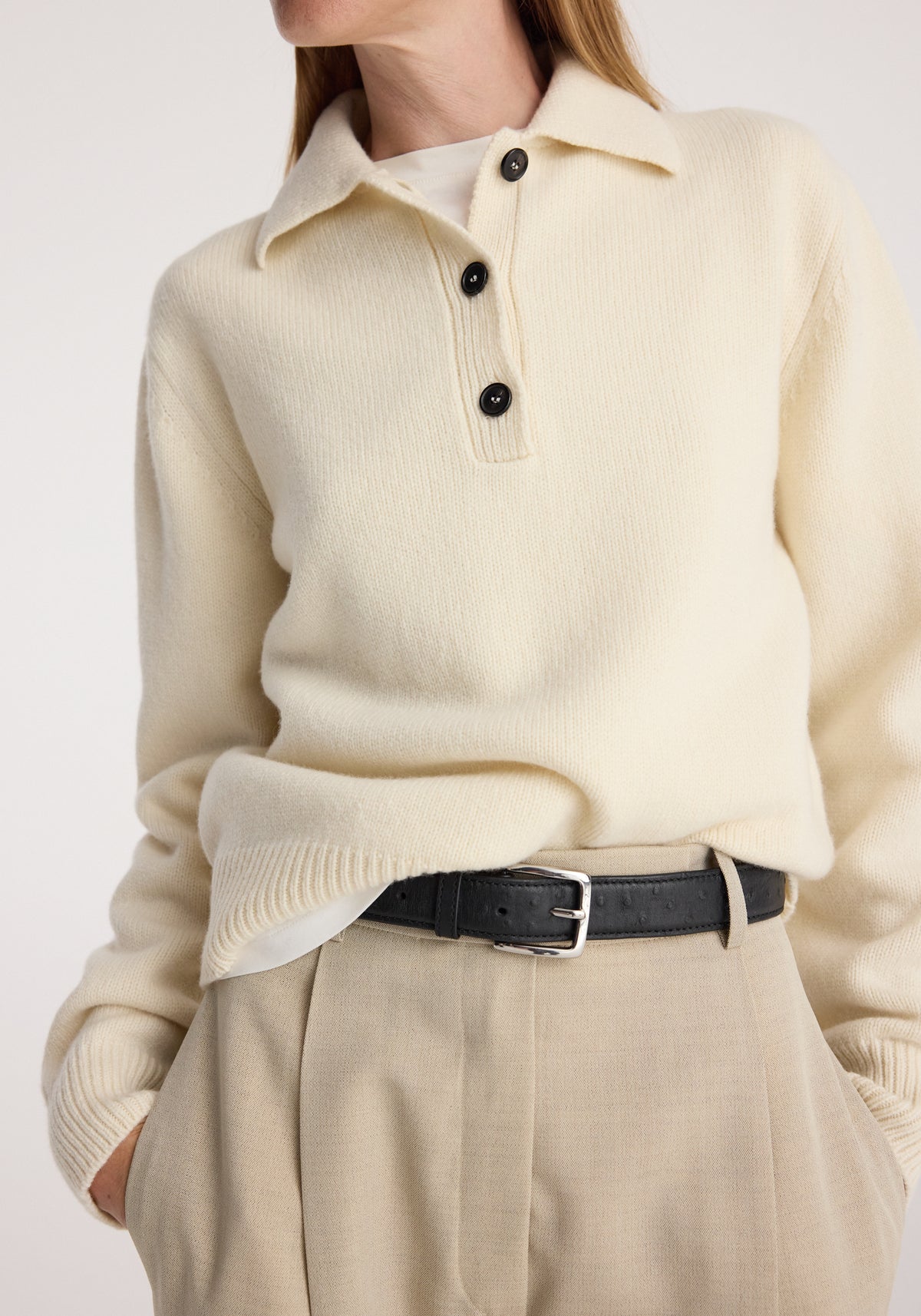 Wool-cashmere polo | cream worn with black belt and beige pleated trousers, featuring a collared neckline, button placket, and relaxed fit